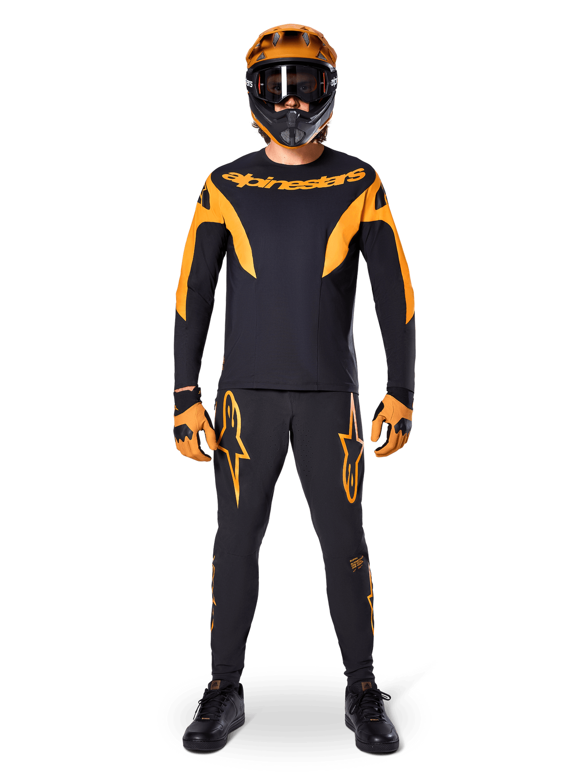 MTB rider wearing Alpinestars A-Supra Race Jersey - Long Sleeve in Black and Orange, matching black and orange pants, gloves, and a full-face helmet with goggles, coordinated mountain bike kit for racing and off-road performance
