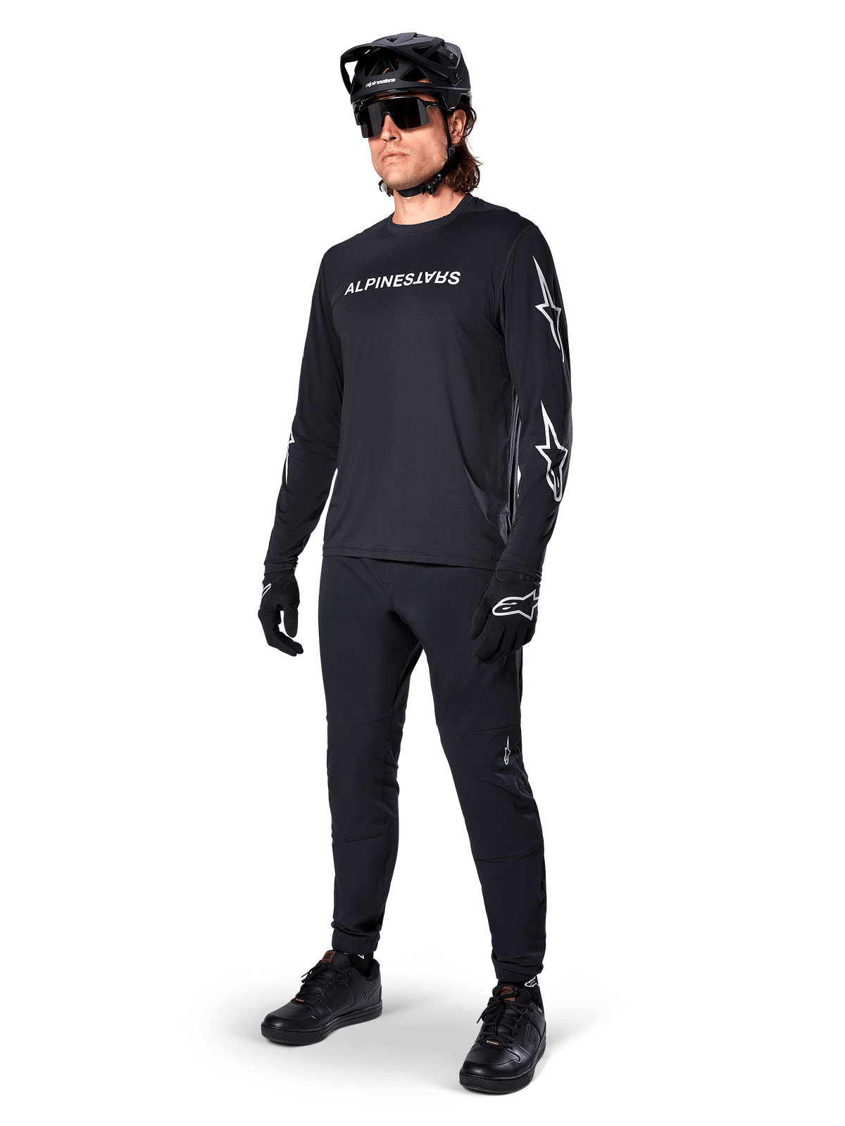 Alpinestars A-Dura Switch långärmad tröja, svart, mountainbiketröja bärs med svarta byxor, hjälm och handskar, vit ordmärkeslogotyp på bröstet och stjärnlogotyper på ärmarna, matchande MTB-utrustning för terrängkörning