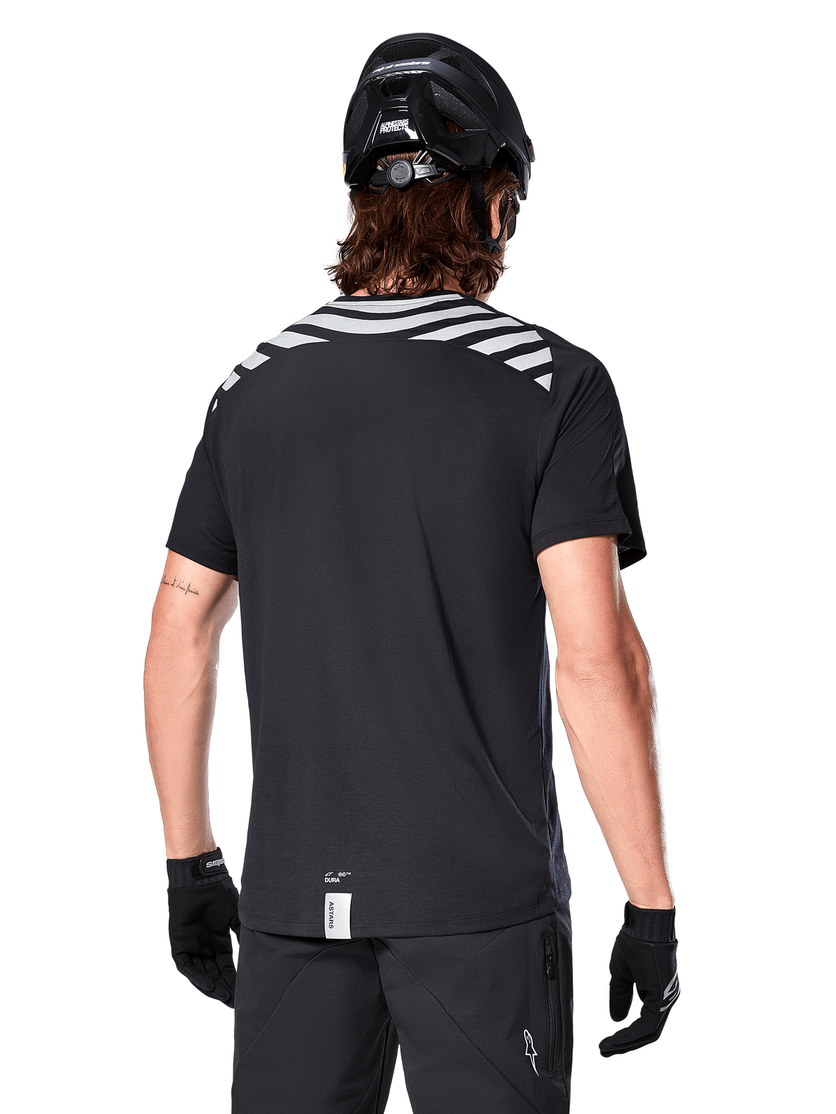 Alpinestars A-Dura Dri Oscar Jersey, Short Sleeve MTB Jersey, Black Reflective, back view on model wearing a cycling helmet and gloves, featuring reflective grey shoulder stripes and a dropped tail, moisture-wicking technical fabric for mountain biking