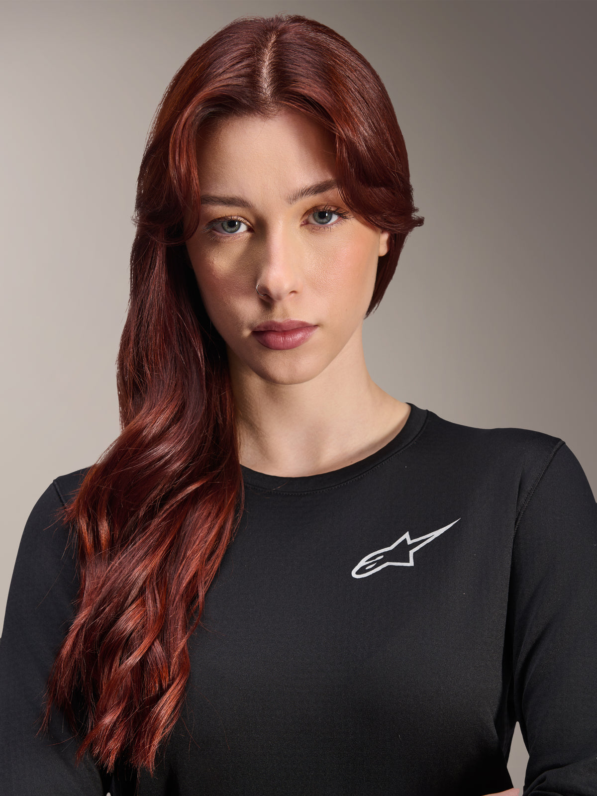 Alpinestars Stella A-Dura Thermal-tröja, långärmad MTB-tröja för dam, svart med vit Alpinestars-logotyp på bröstet, närbildsporträtt av en kvinna med långt rött hår, cykelkläder för svalt väder
