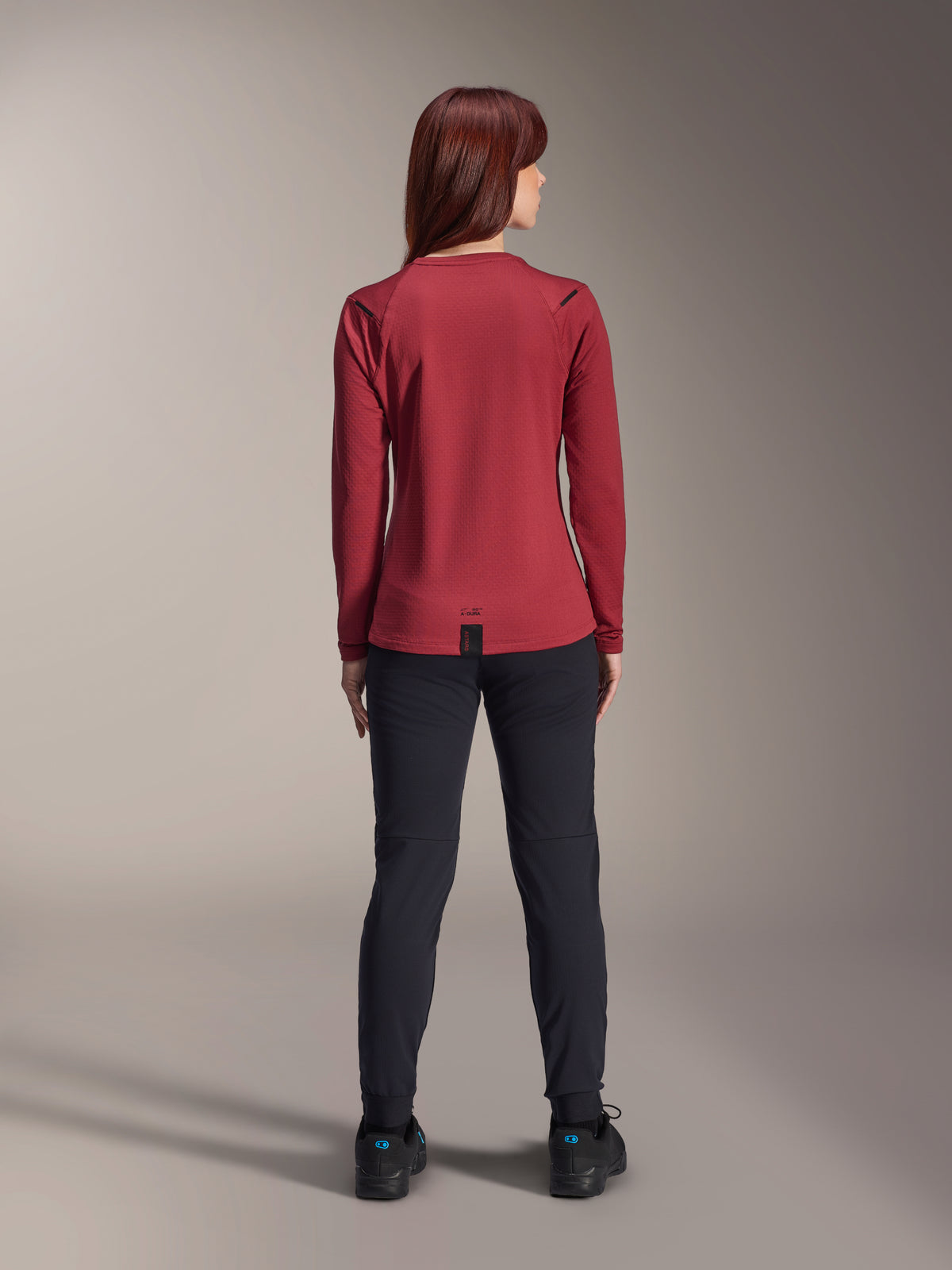 Alpinestars Stella A-Dura Thermal Pants, mountainbikebyxor för dam, svarta, bärs med en vinröd långärmad termotröja, vy bakifrån som visar den tekniska passformen och konstruktionen för cykling i kallt väder.