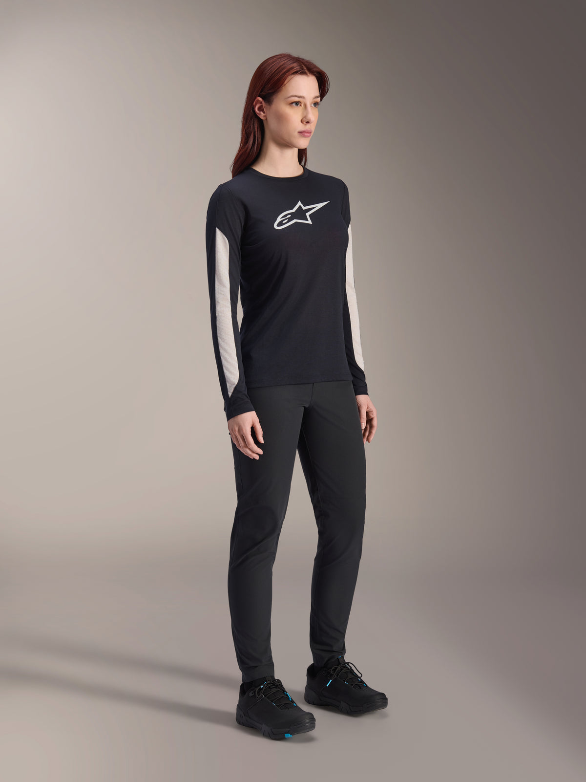 Alpinestars Stella A-Dura Dri Astar långärmad tröja för dam, svart, med vita meshpaneler på ärmarna och vit Astar-logotyp, bärs med svarta byxor och skor, tekniska cykelkläder för mountainbike
