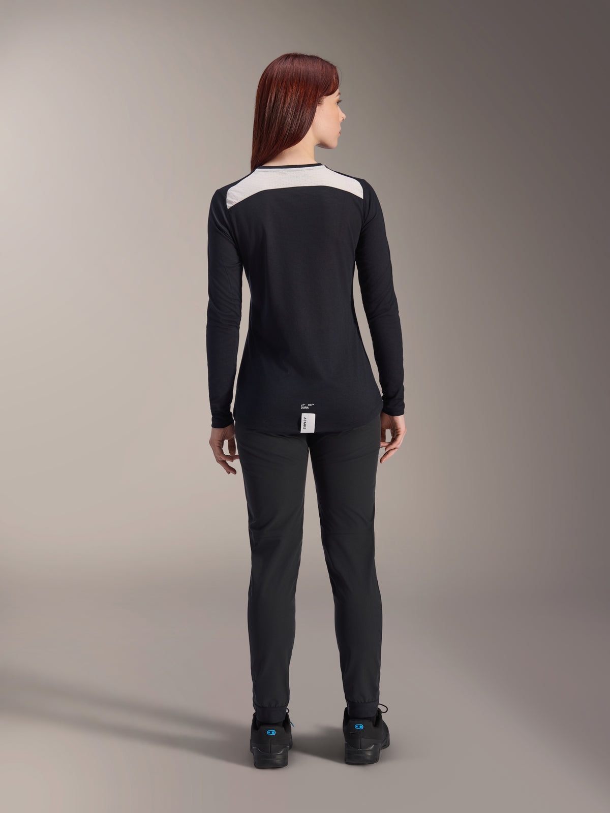 Alpinestars Women Stella A-Dura Pants and Stella A-Dura Elite Jersey, MTB riding gear, Black with white shoulder panel, viewed from behind, technical outdoor apparel for mountain biking, paired with black shoes