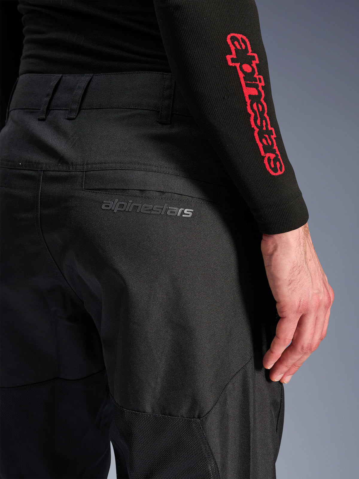 Alpinestars C-1 Air byxor, svarta motorcykelbyxor i textil, närbild på bakfickan med en diskret grå Alpinestars-logotyp, med ventilerande meshpaneler och slitstarkt polytyg, designade för bekväm stadskörning