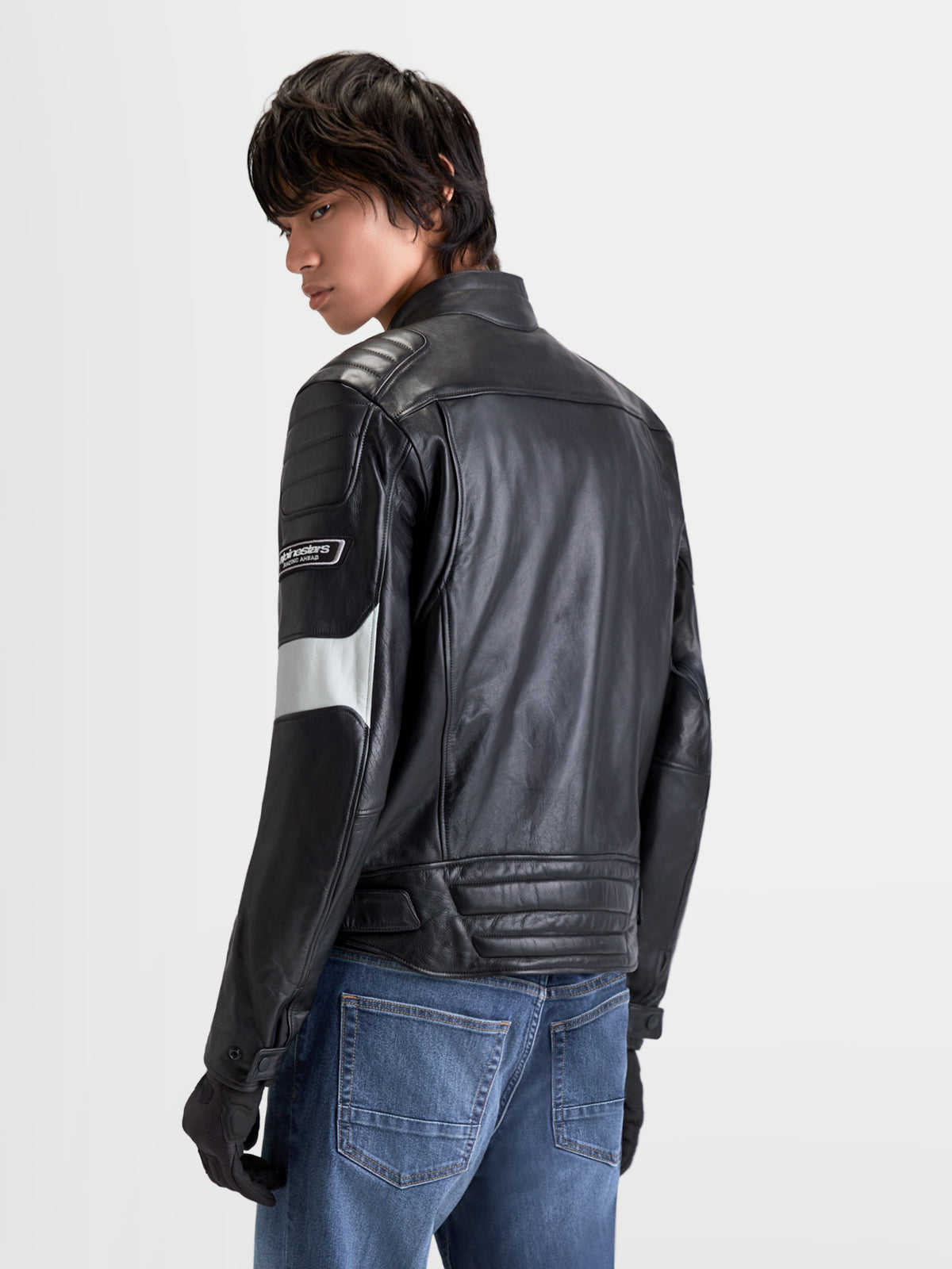 Alpinestars Revern läderjacka, urban motorcykeljacka i läder för herr, svart och metallsilversfärgad, vy bakifrån på modell som bär jeans, visar vintagebehandlad läderkonstruktion och klassisk stil