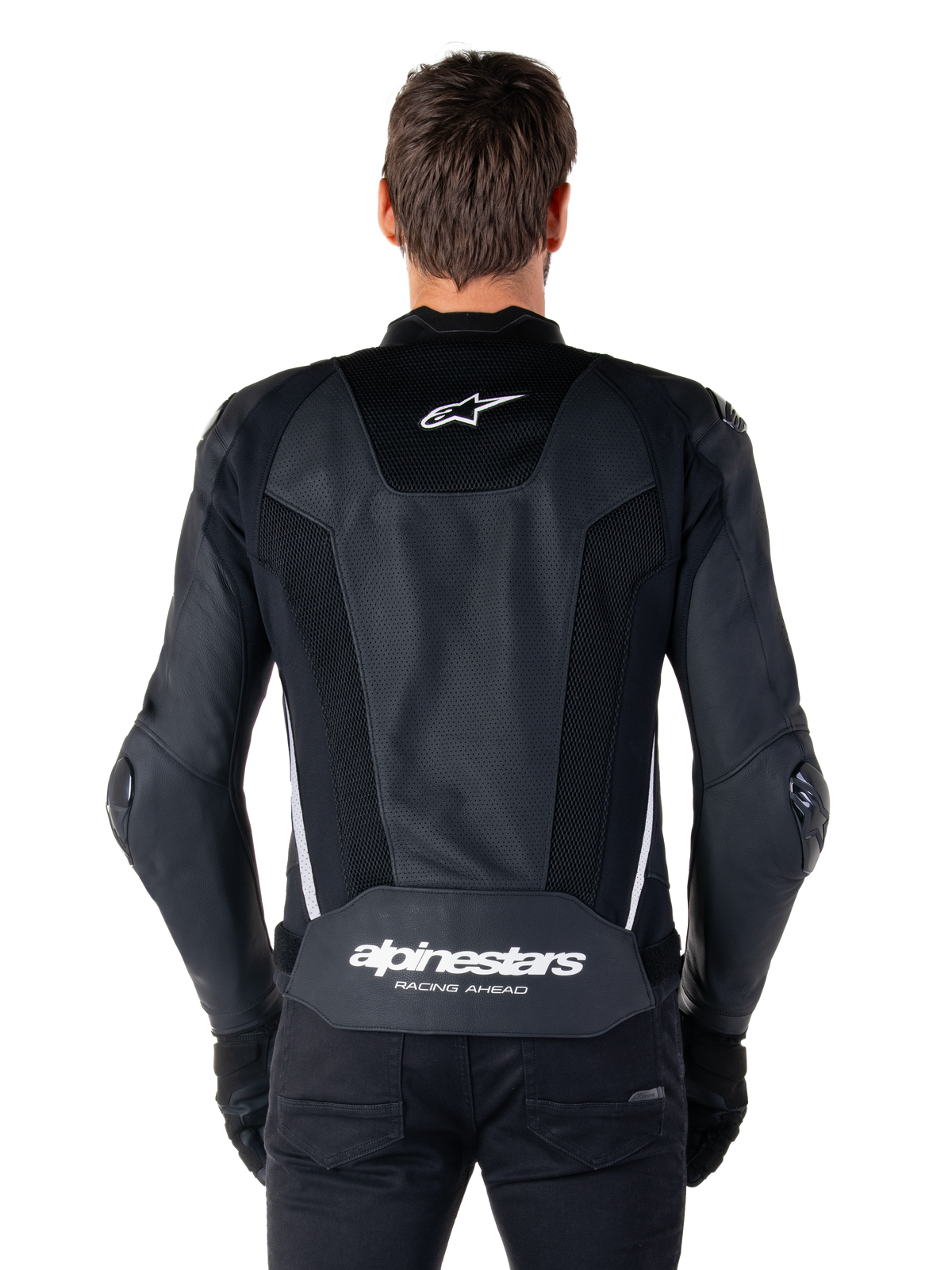 Alpinestars Missile V3 Airflow läderjacka, svart och vit, sedd bakifrån på en förare, med omfattande perforerade läderpaneler, vita sidodetaljer, Alpinestars stjärnlogotyp på den övre delen av ryggen och 'alpinestars RACING AHEAD'-logotyp på den nedre delen av ryggen.