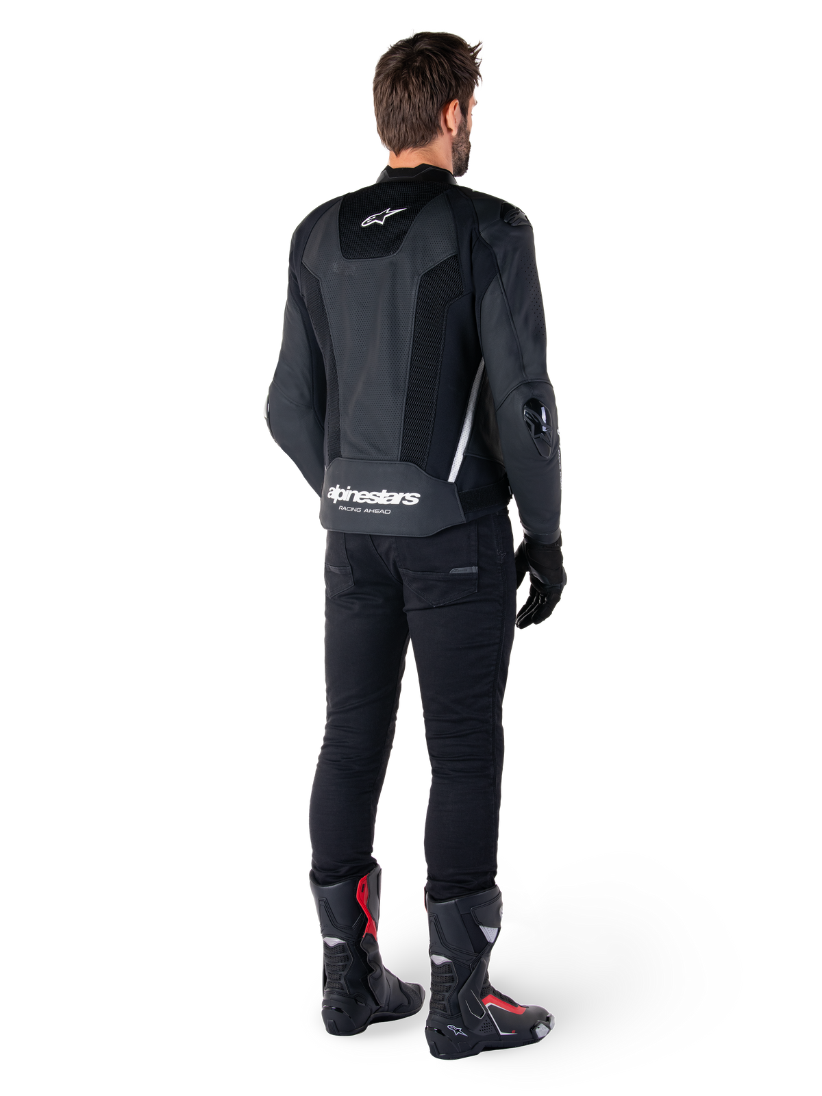 Alpinestars Missile V3 Airflow skinnjacka, svart och vit, vy bakifrån buren med svarta tekniska byxor och racingstövlar, med perforerade läderpaneler på ryggen och tydlig Alpinestars-logotyp på nedre delen av ryggen.