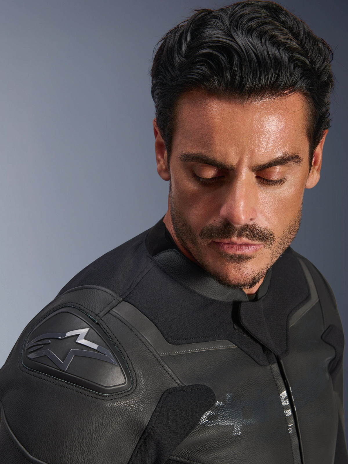 Alpinestars GP Force V2 läderjacka, svart, närbild av en manlig modell som bär jackan, fokus på axeln med GP Lite Evo DFS-skydd och Alpinestars-logotyp, förstklassig läderkonstruktion med flera paneler