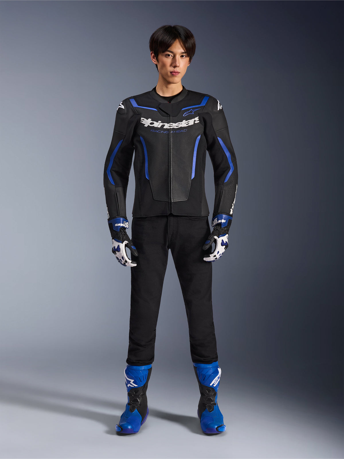 Alpinestars GP Force V2 Airflow läderjacka i Black Metallic Blue, matchande racinghandskar, svarta byxor och blå stövlar, professionell sportig motorcykelutrustning, helkroppsbild i studiomiljö
