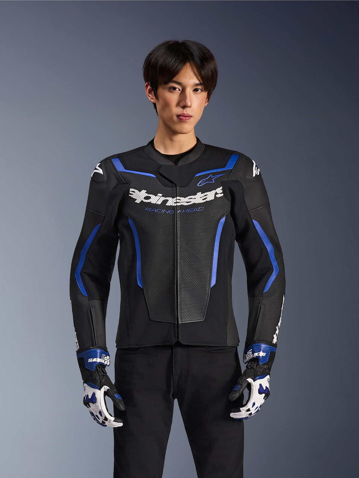 Alpinestars GP Force V2 Airflow läderjacka, Black Metallic Blue, motorcykeljacka med perforerat läder och blå detaljer, bärs av en modell med matchande racinghandskar och svarta byxor, professionell sportig körutrustning