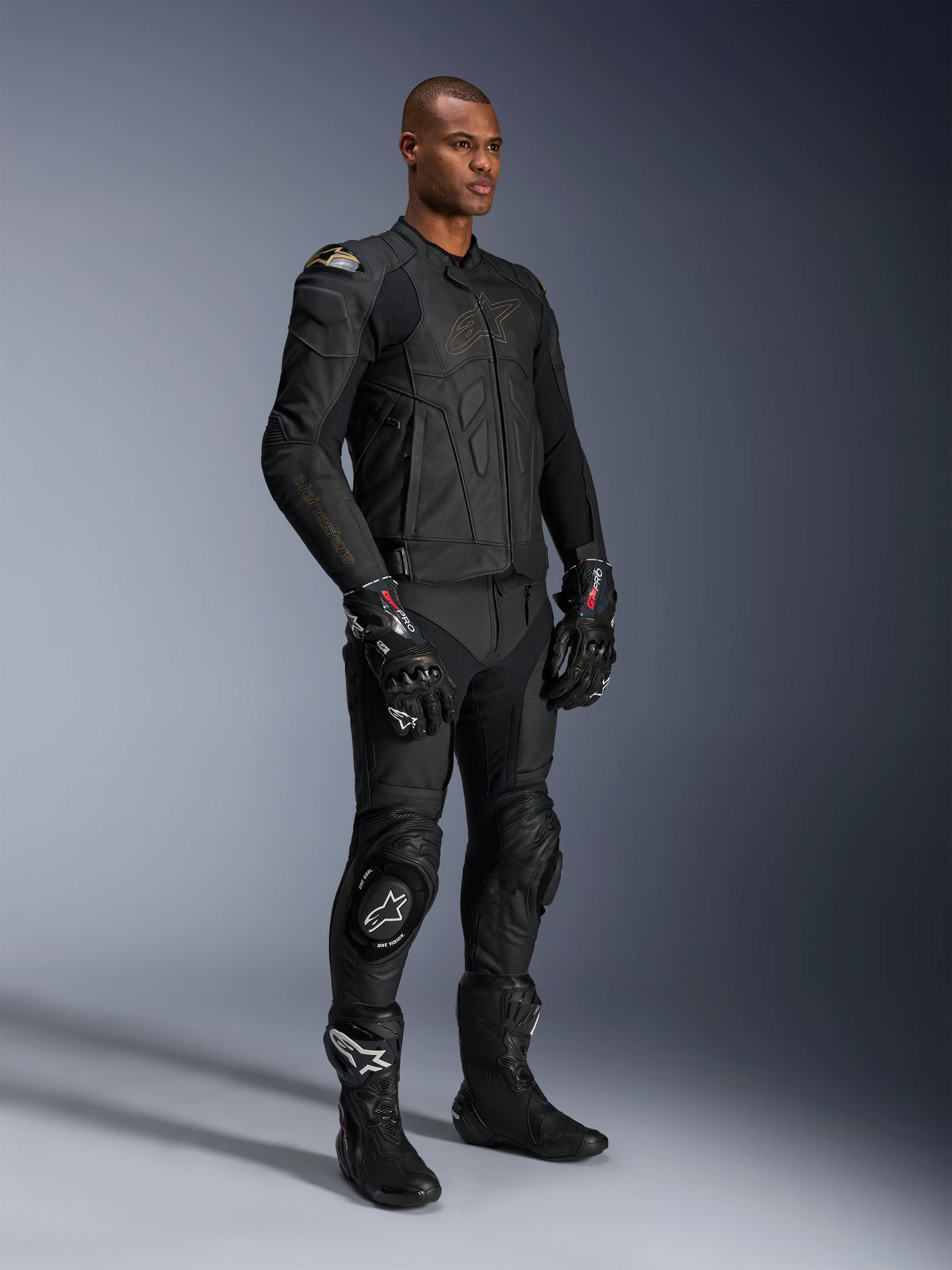 Manlig modell klädd i Alpinestars Missile V3 läderbyxor och matchande svart läderjacka med gulddetaljer, svarta GP Pro racinghandskar och svarta racingstövlar, komplett motorcykelutrustning för väganvändning, studiobild