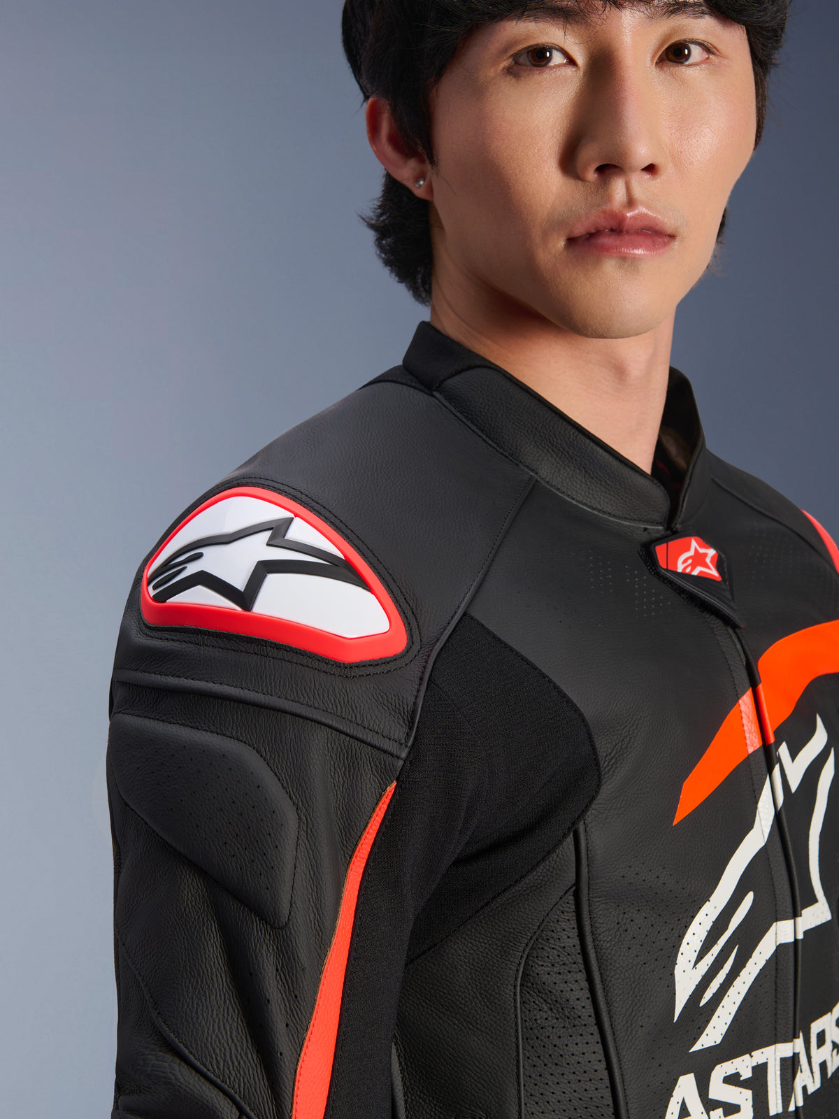Alpinestars GP Plus R V4 Airflow läderjacka, svart röd fluo vit, närbild på modell som bär jackan, med framträdande Astar-logotyp på axelskyddet och perforerat läder på bröstet för maximalt luftflöde, professionella motorsportkläder