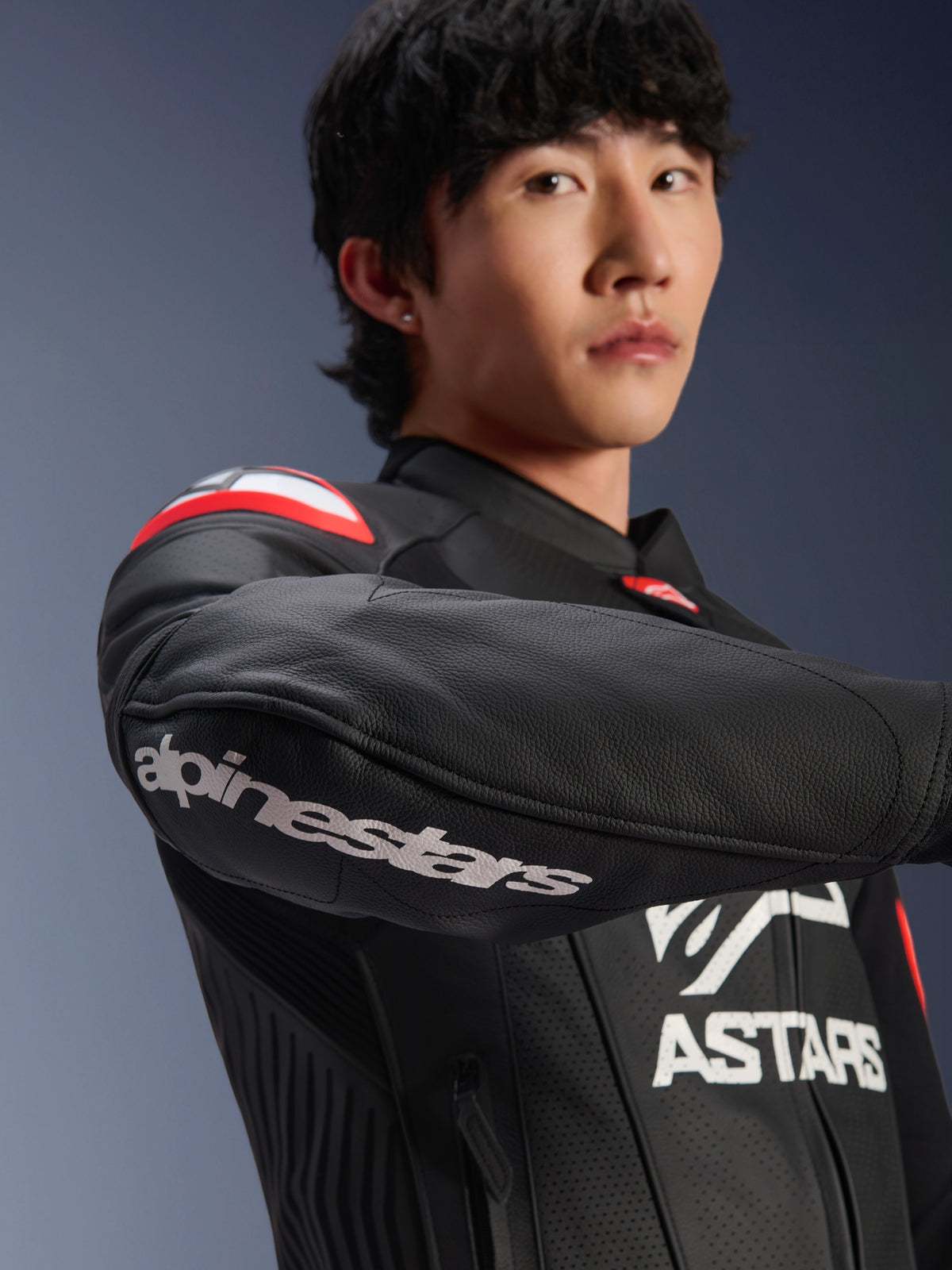 Alpinestars GP Plus R V4 Airflow skinnjacka, motorcykeljacka, svart med röd fluo och vita detaljer, bärs av modell, närbild på ärmen med vit Alpinestars-logotyp, röda och vita axeldetaljer, perforerat läder för ventilation, professionell racing-inspirerad design
