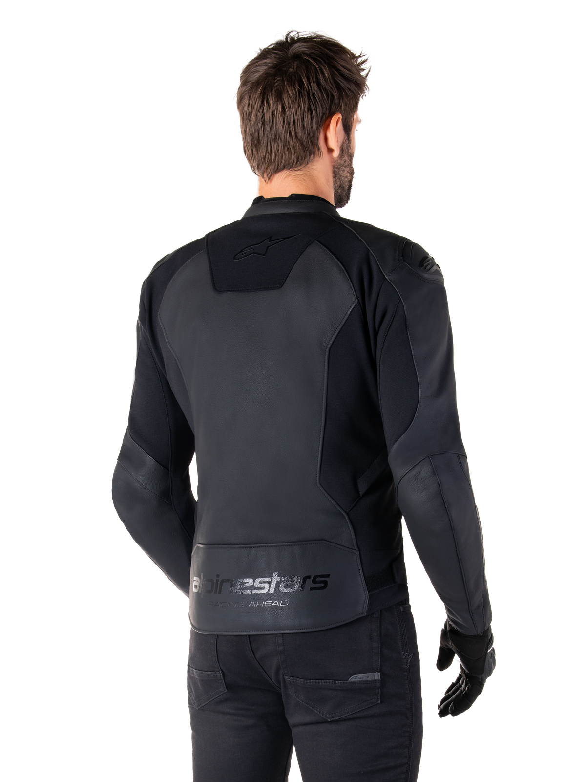 Alpinestars Faster V3 Skinnjacka, Svart, ryggvy av modell som bär den sportiga motorcykeljackan, med 'alpinestars' och 'RACING AHEAD' logotyper på nedre ryggen, premiumläder med matta paneler, modern sportig silhuett för motorcykelkörning