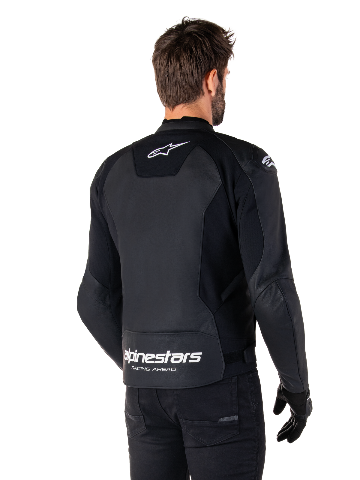 Alpinestars Faster V3 Skinnjacka, svart och vit, vy bakifrån på en förare, med vit stjärnlogotyp på övre ryggen och stor Alpinestars-logotyp med ”Racing Ahead” på den nedre delen, förlängd rygg för täckning vid körning, förstklassig skinnkonstruktion för sportkörning