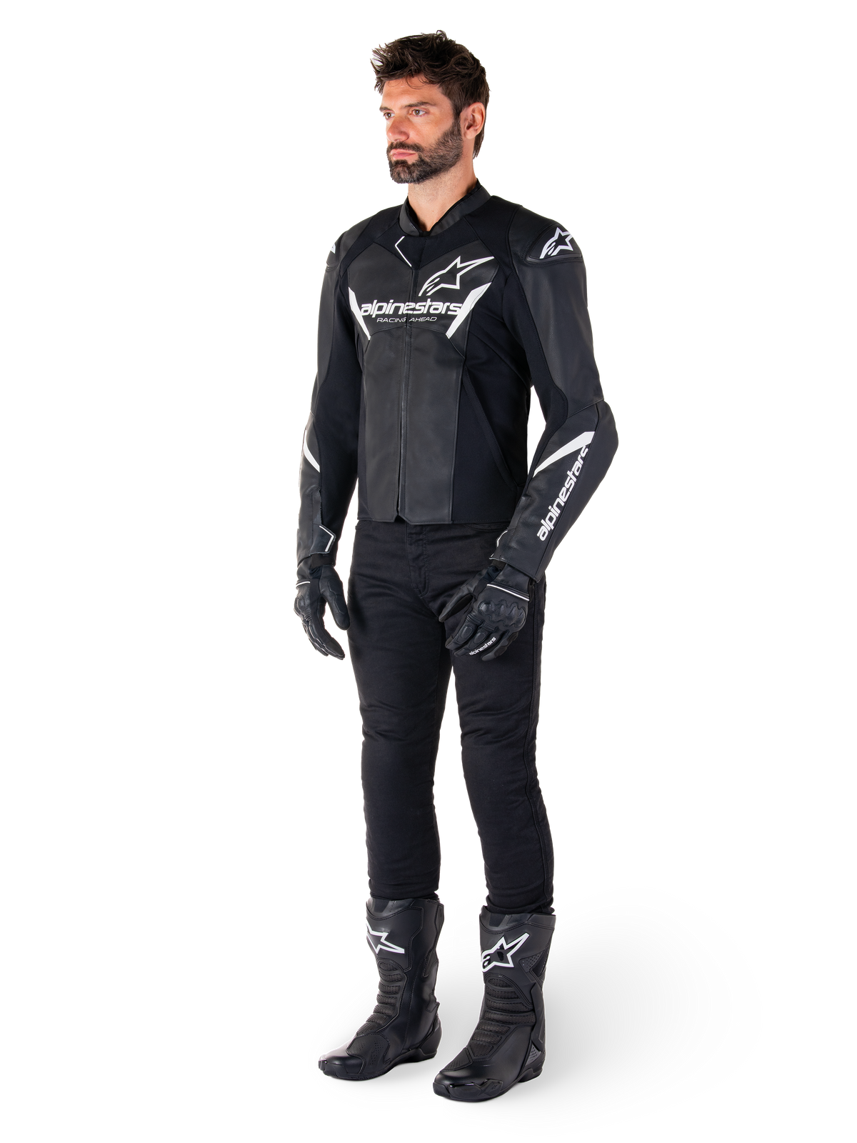 Manlig modell iklädd Alpinestars Faster V3 skinnjacka, sportjacka för motorcykelkörning, svart och vit, kombinerad med svarta motorcykelbyxor, handskar och stövlar, med vita logotyper, sportpassform för road racing