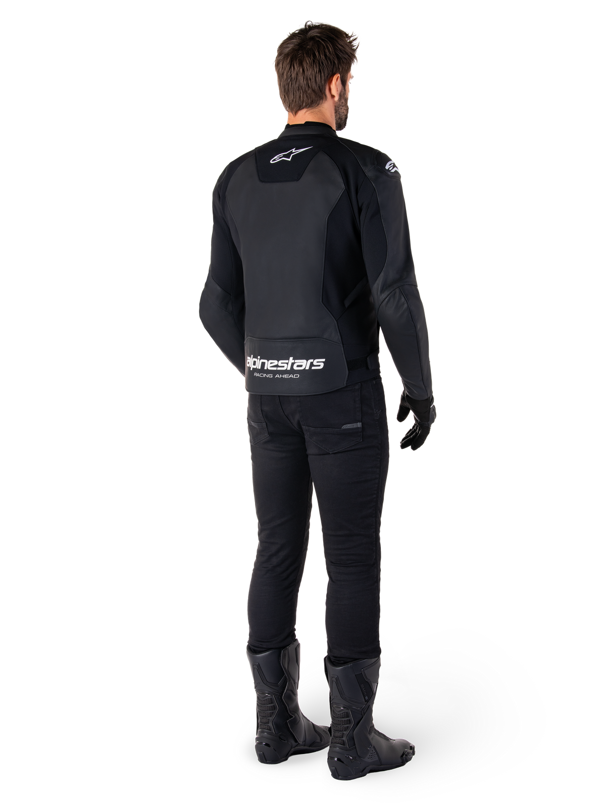 Alpinestars Faster V3 skinnjacka, baksida, svart och vit, med 'alpinestars RACING AHEAD'-logotyp på nedre delen av ryggen, bärs med svarta mc-byxor och stövlar, sportinfluerad mc-jacka i skinn med stretchpaneler.