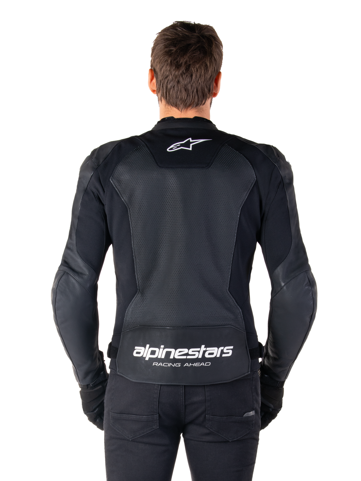 Alpinestars Faster V3 Airflow Skinnjacka, svart och vit, vy bakifrån av en förare som visar den perforerade ryggpanelen i läder för ventilation, vit Alpinestars-logotyp på övre delen av ryggen och 'RACING AHEAD'-märkning på nedre delen av ryggen, sportig motorcykelutrustning.