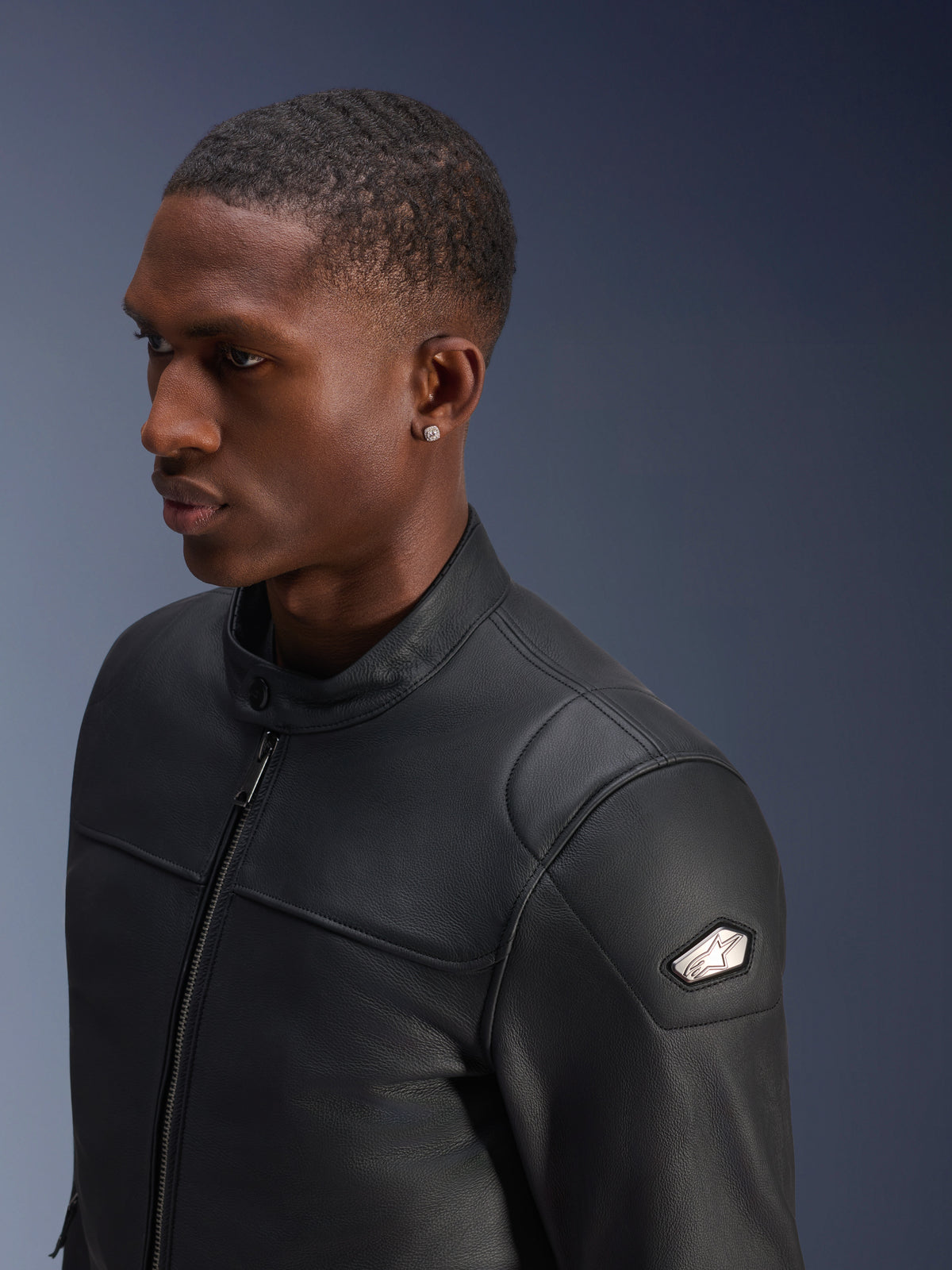 Alpinestars Blacktrack läderjacka, svart urban motorcykeljacka i nötläder för herr, närbild med metalliskt axelmärke.