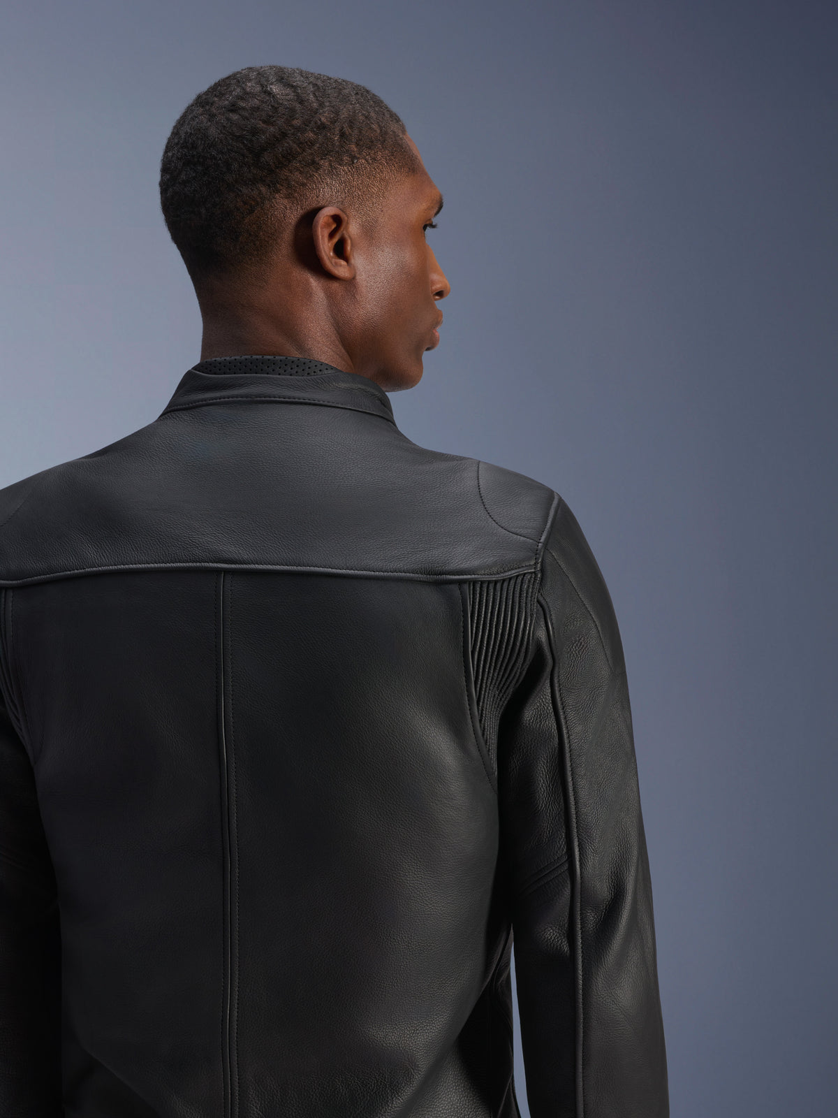 Alpinestars Blacktrack skinjacka, svart urban motorcykeljacka i läder, vy bakifrån med dragspelspaneler.