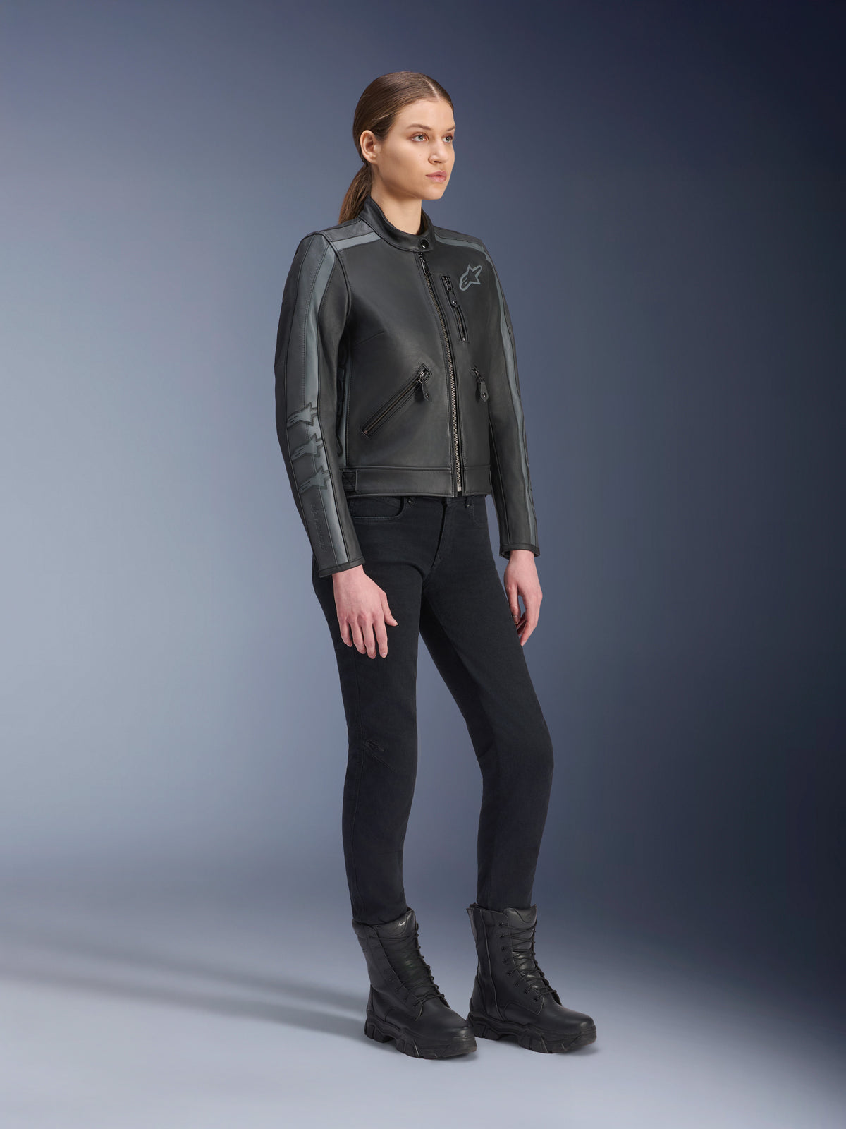Alpinestars Stella Dyno skinnjacka, mc-jacka för dam, Black Tar Gray och mörkgrå, bärs med svarta mc-byxor och stövlar, med grå racingränder på ärmarna och heritage-läderdesign