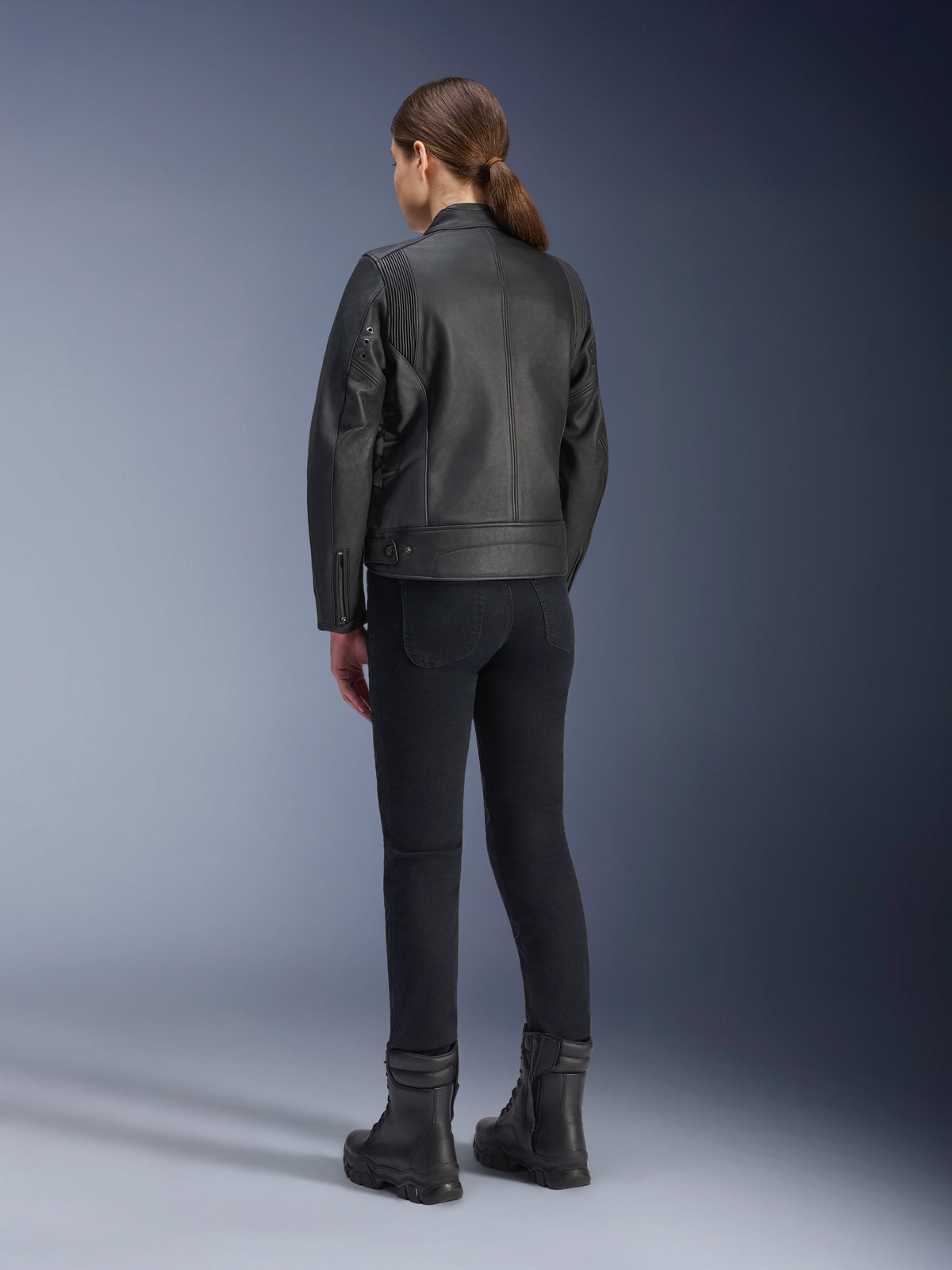 Alpinestars Stella Dyno läderjacka, motorcykeljacka för dam, svart, vy bakifrån som visar premiumläderkonstruktion och skräddarsydd passform, buren med svarta körbyxor och svarta stövlar, urban körstil.