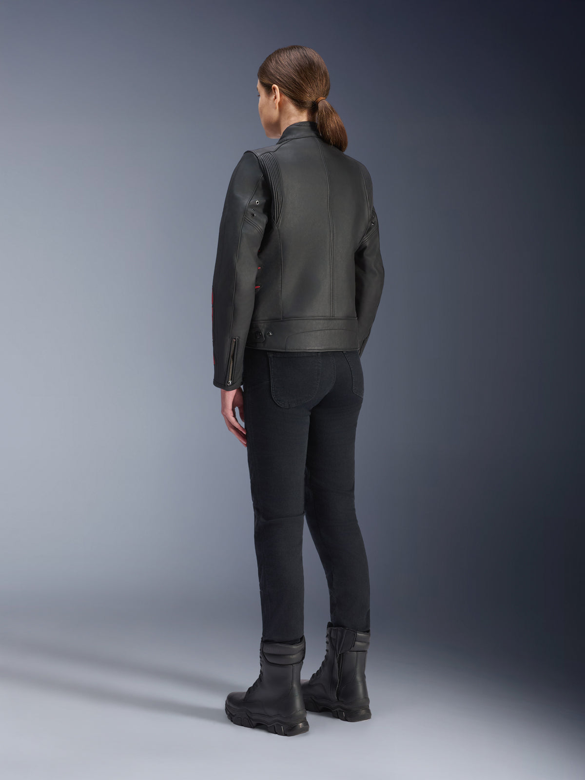 Alpinestars Stella Dyno läderjacka, motorcykeljacka för dam, Black Haute Red, vy bakifrån, buren med svarta körbyxor och svarta stövlar, premiumläderfinish med heritage-stil