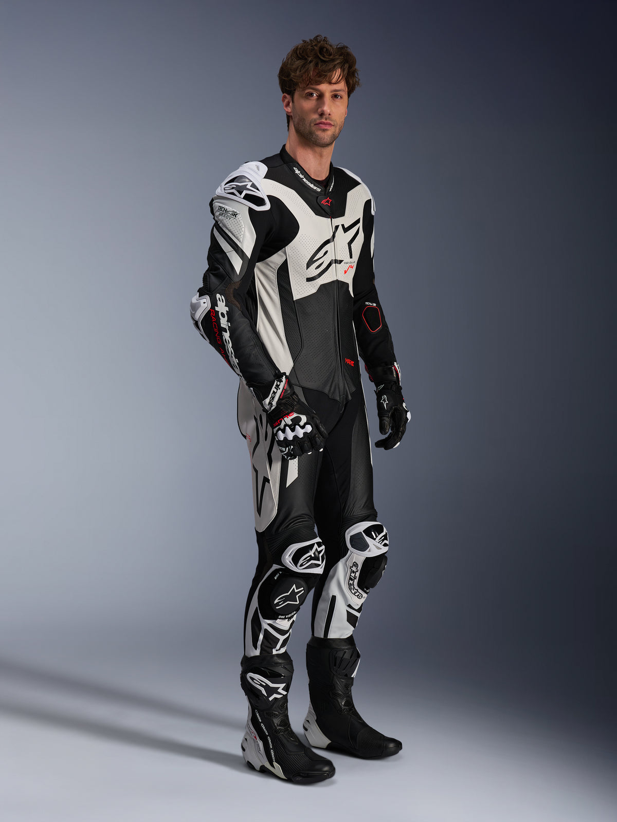 Alpinestars GP Plus V4 Sprint skinnställ, herr-racingoverall i svart, vit och röd fluo, Tech-Air®-redo, bärs av modell i full racingutrustning.