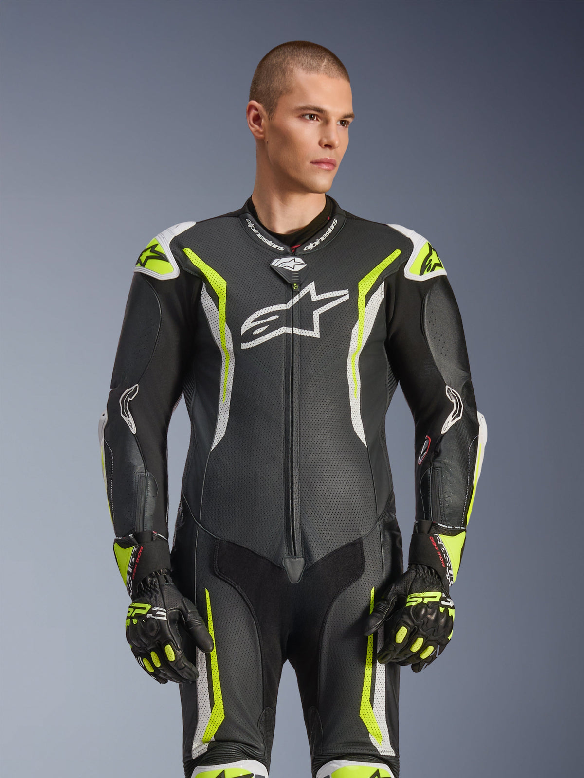 Alpinestars GP Tech V5 One Piece Leather Suit, Black White and Yellow Fluo, professional racing gear, perforated leather with large white Astar logo on chest, fluorescent yellow and white accents, worn with matching racing gloves