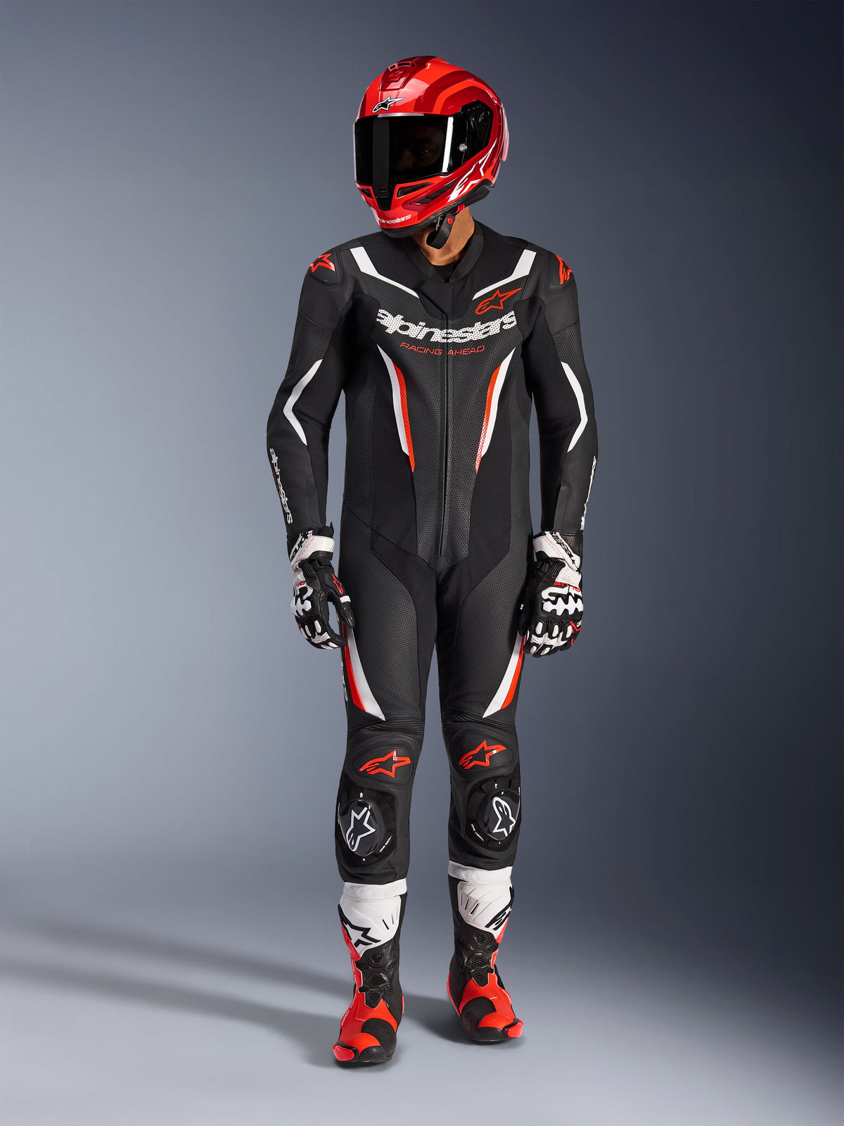 Alpinestars GP Force V2 Leather Suit - 1Piece, Black White and Red Fluo, worn with a red racing helmet, black and white gloves, and red and black boots, featuring perforated leather panels and Alpinestars branding, professional motorcycle racing gear