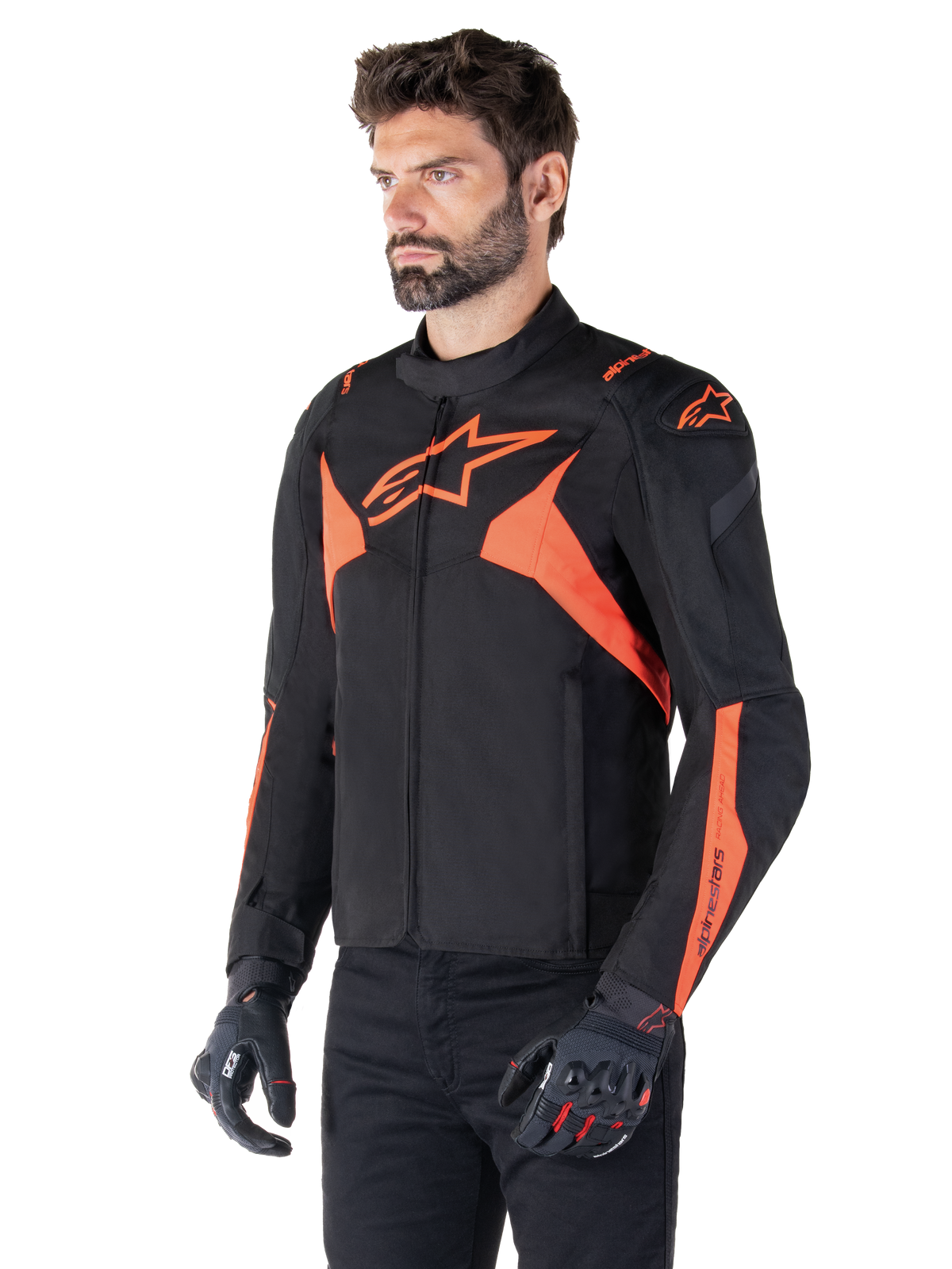 Alpinestars T-Jaws V4 Waterproof Jacket, svart och röd fluo, sportmotorcykeljacka buren av en manlig modell, med framträdande orangea stjärnlogotyper på bröstet och axlarna, matchad med svarta handskar och byxor