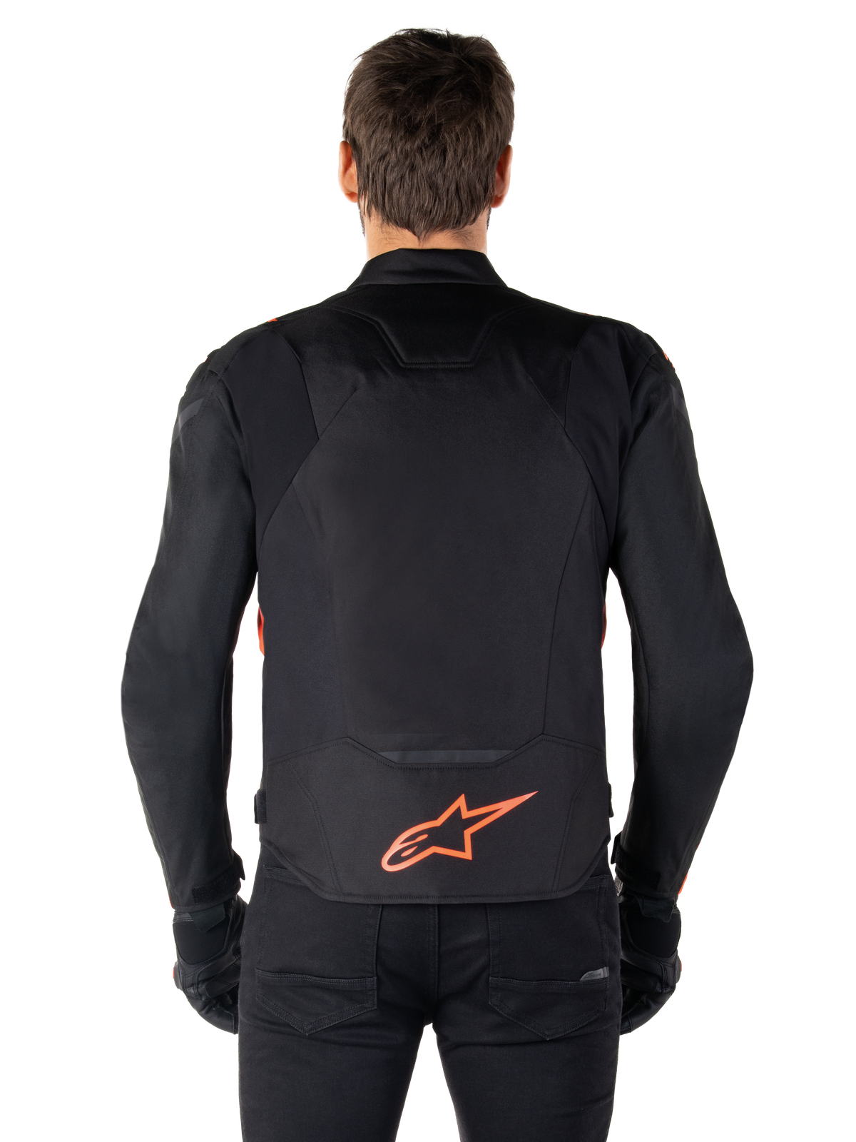 Alpinestars T-Jaws V4 Waterproof Jacket, sedd bakifrån, svart med röd fluo, röd Alpinestars-logotyp på nedre delen av ryggen, teknisk textilkonstruktion, bärs med svarta byxor och handskar för en komplett sportig look