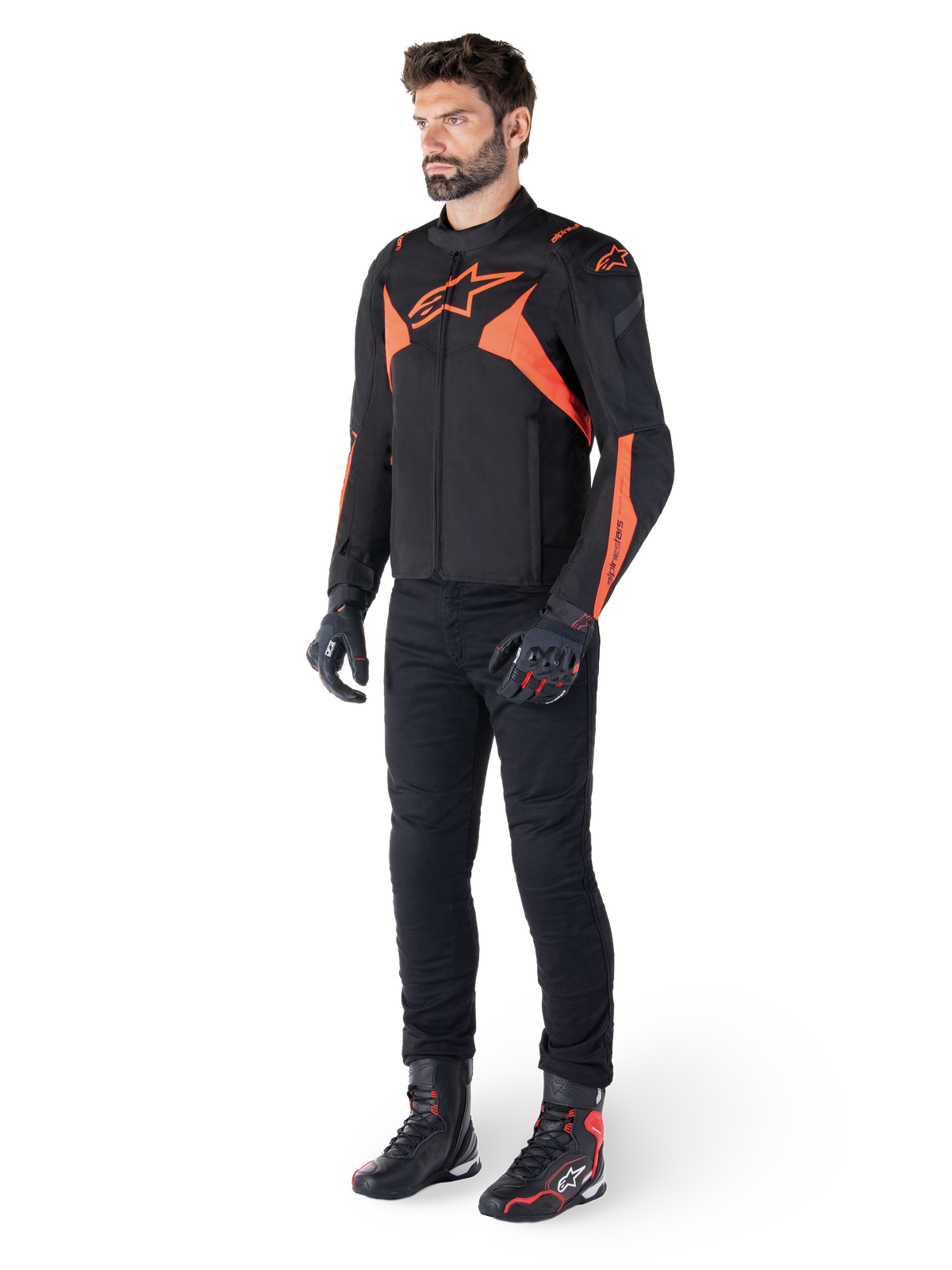 Alpinestars T-Jaws V4 Waterproof Jacket, svart och röd fluo, bärs av en manlig modell med svarta byxor, handskar och stövlar, med lysande orangea detaljer och Alpinestars-logotyp, sportig design för motorcykelkörning