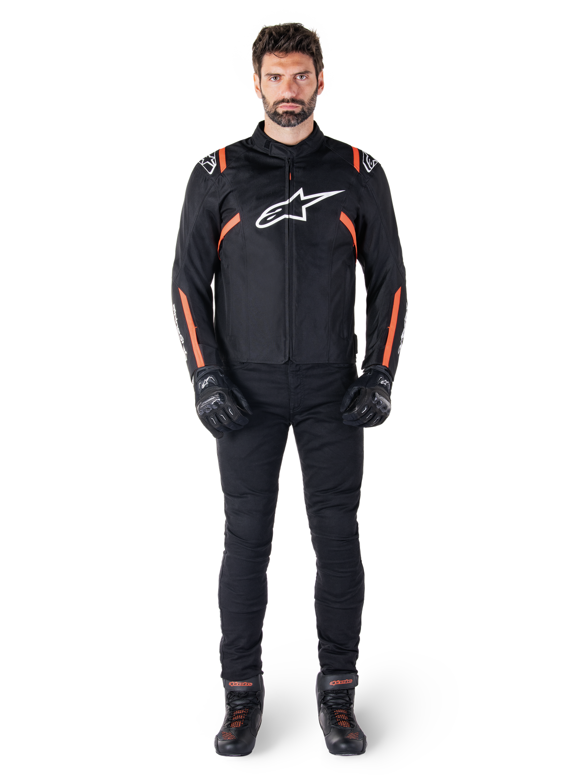 Manlig modell som bär Alpinestars T-SPS V2 Waterproof-jacka i Black White Red Fluo, kombinerad med svarta motorcykelbyxor och handskar, med en vit Alpinestars-logotyp på bröstet och röda detaljer på ärmarna.