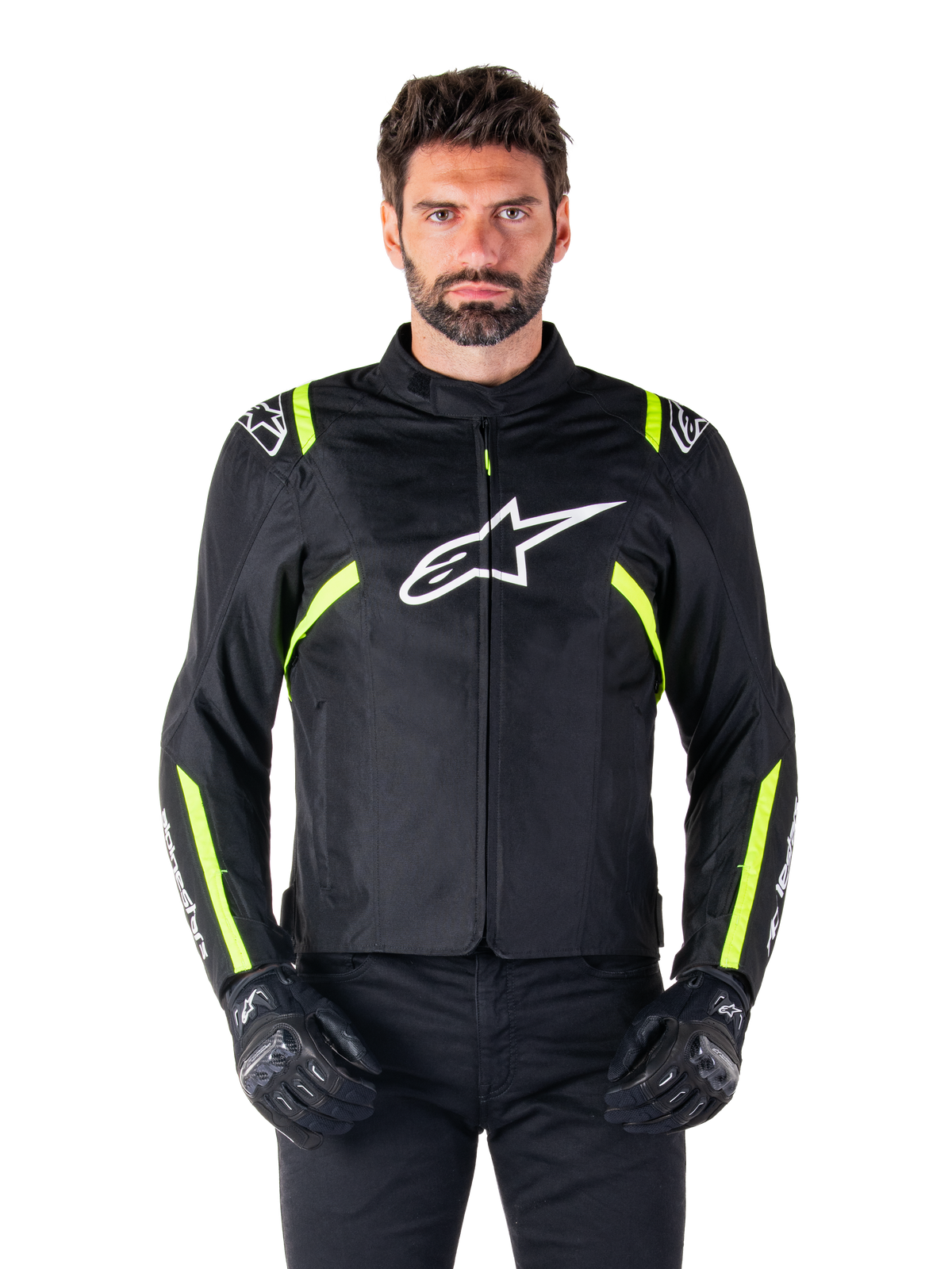 Alpinestars T-SPS V2 Waterproof Jacket, motorcykeljacka, svart med vita och neongula detaljer, bärs av en modell med svarta handskar, vit stjärnlogotyp på bröstet och neongula ränder på ärmar och axlar, sportig textilutrustning för körning i alla väder