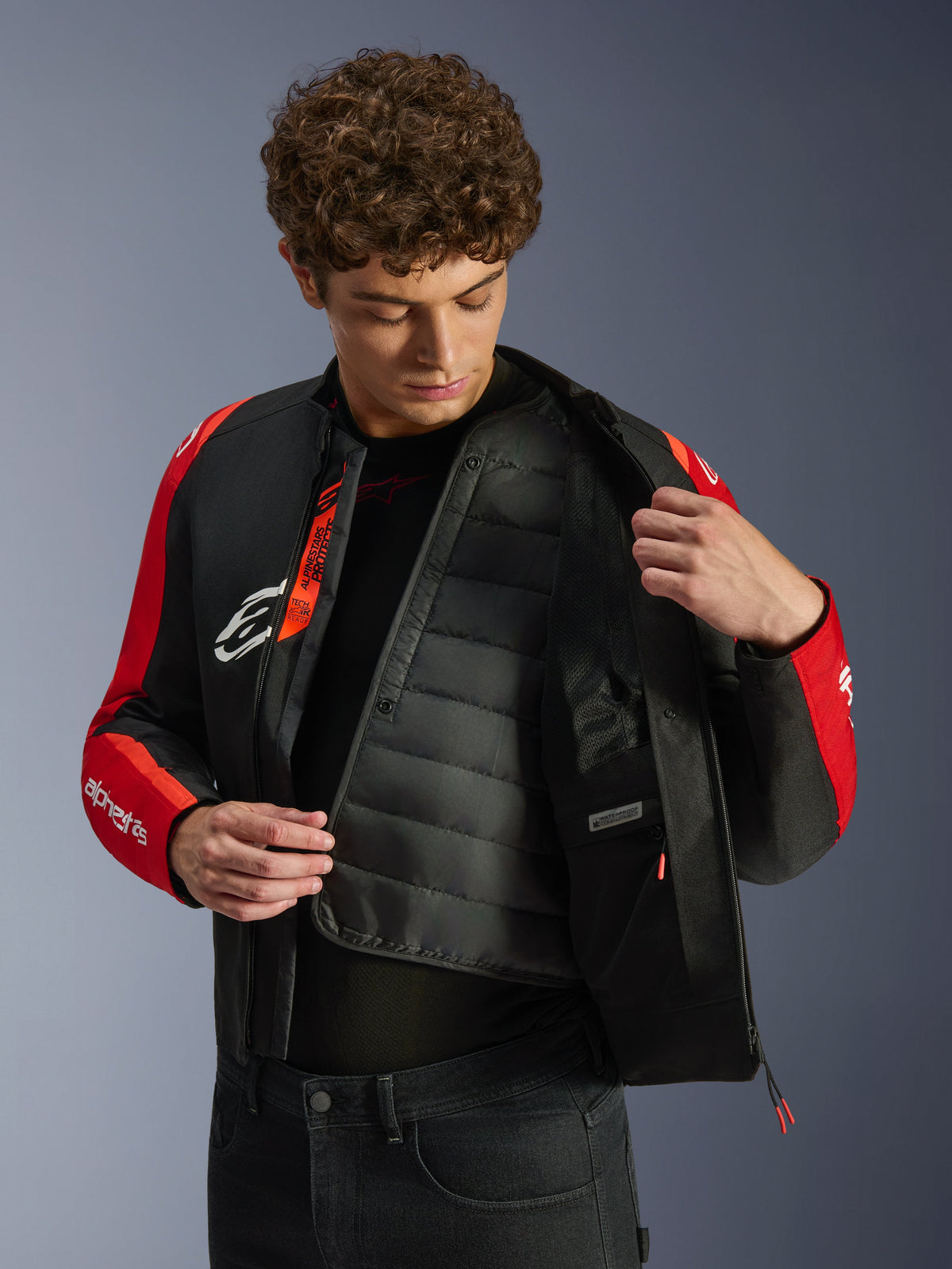Alpinestars T-SPS V2 Waterproof Jacket, svart och röd, med en modell som visar det invändiga kviltade termofodret och det vattentäta facket, Tech-Air Ready-märkning på insidan, sportskuren motorcykeljacka.