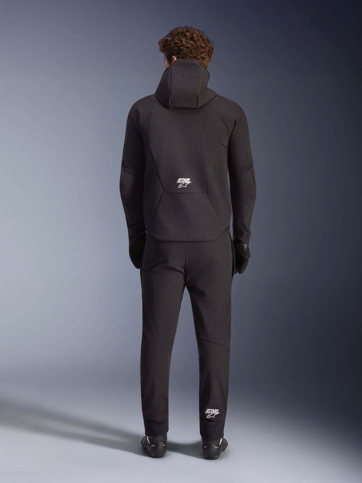 Alpinestars Aeroshell vattentät jacka, svart softshell-mc-jacka för herr, vy bakifrån med huva och vit ASTARS-logotyp.