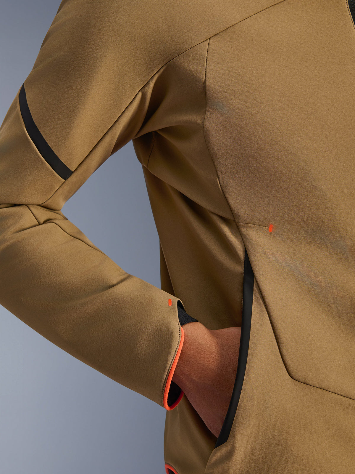 Närbild av Alpinestars Aeroshell Waterproof Jacket, mörk khaki med svarta och fluorescerande orange detaljer, detalj av den dolda handfickan med dragkedja och ärmslut, stretchigt softshell-material för motorcykelkörning