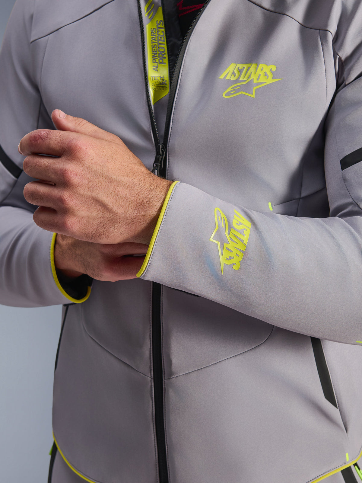 Alpinestars Aeroshell Waterproof Jacket, mellangrå med neongula detaljer, närbild på bröstet och ärmslutet som visar neongula Astars-logotyper, detalj av den inre fliken med Tech-Air Ready-märkning, modern sportig softshell-motorcykeljacka