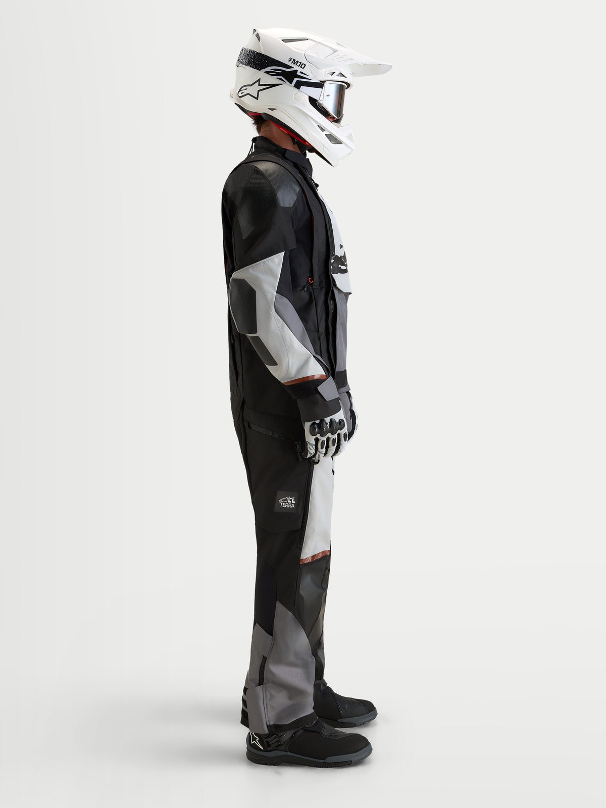 Alpinestars Harok V2 Drystar jacka, äventyrsmotorcykeljacka för herr, mörkgrå, isgrå och svart, bärs med vit hjälm och äventyrsutrustning i studio, sidovy
