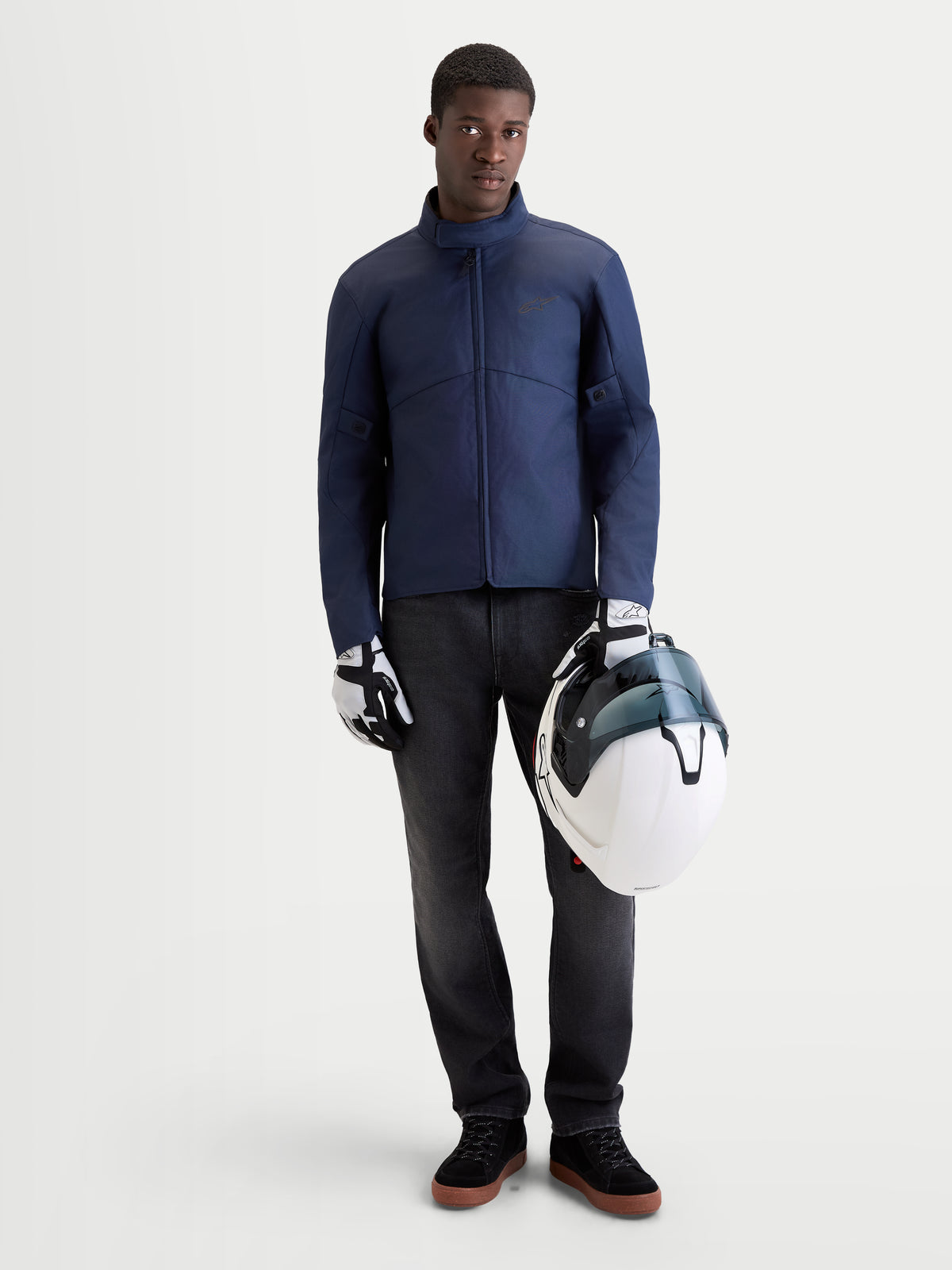 Alpinestars C 1 Waterproof jacka, mörkblå urban motorcykeljacka för herr, framifrån på modell som bär matchande handskar och håller i en vit hjälm