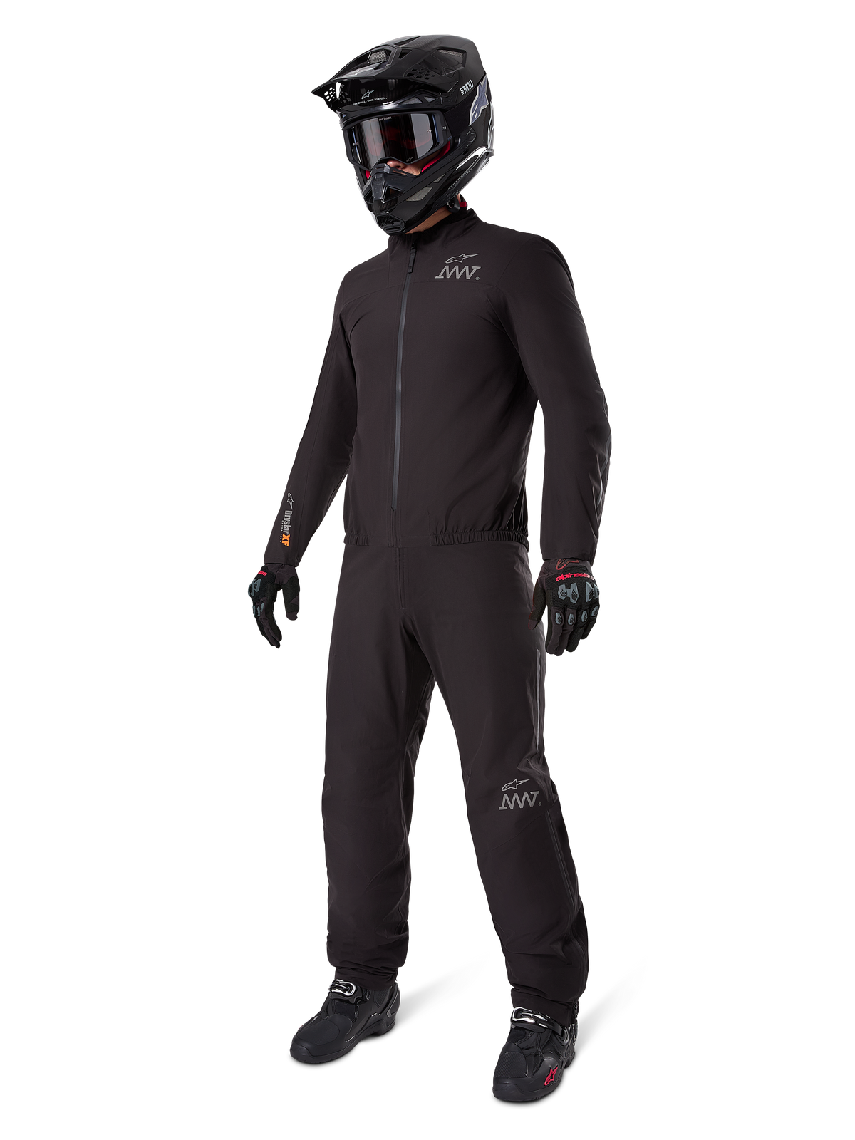 Alpinestars AMT-8 Stretch Drystar® XF Liner, black waterproof motorcycle suit, worn with black helmet, goggles, and gloves, featuring AMT and Drystar XF branding, functional adventure gear for all-weather protection.