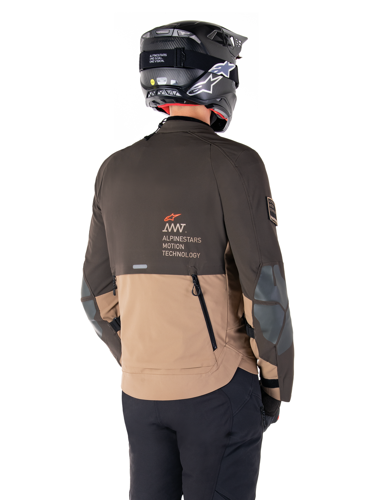 Alpinestars AMT-8 Stretch Drystar® XF-jacka, äventyrsmotorcykeljacka, mörkbrun och mörk khaki, vy bakifrån som visar AMT Alpinestars Motion Technology-logotyp, tvåfärgad textildesign med ventilationsdragkedjor bak och ryggutblås i skifferdesign, bärs med svart hjälm och körbyxor