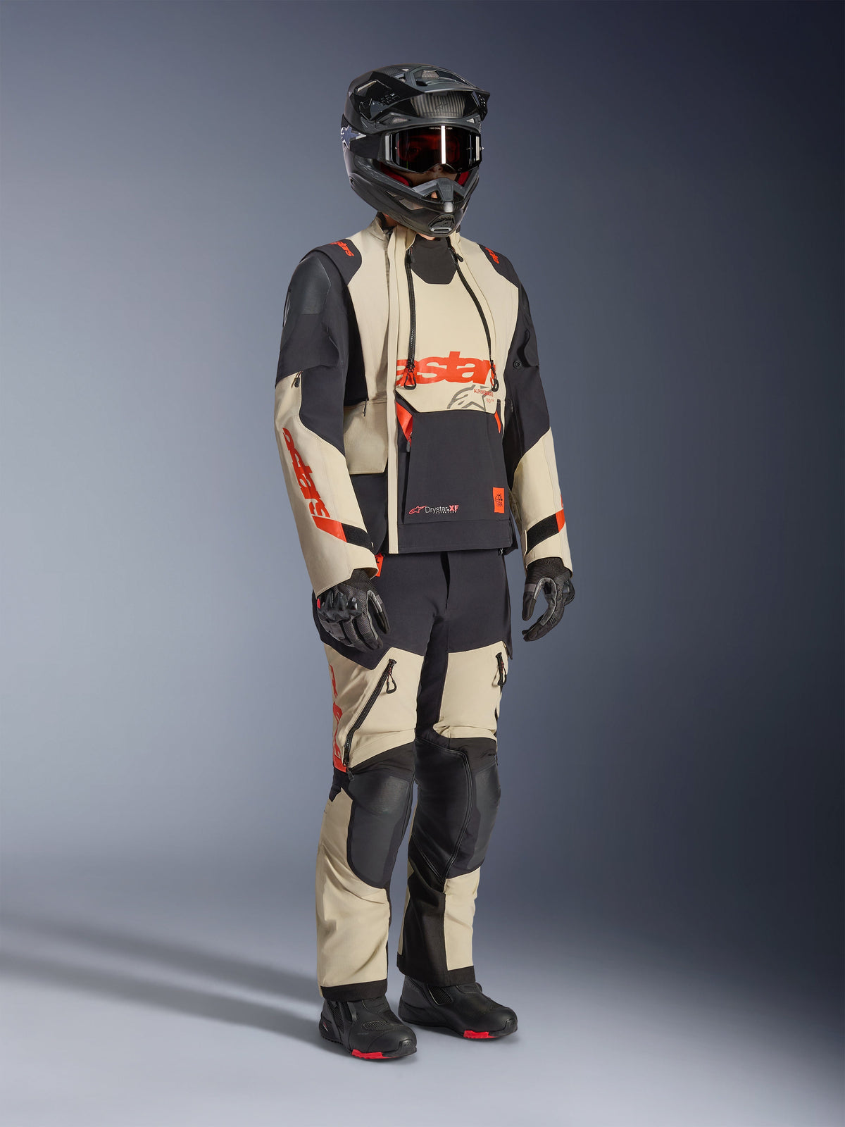 Alpinestars Halo Pro Drystar® XF laminerad jacka i Mastic Black, äventyrsmotorcykeljacka buren med matchande byxor, helhjälm, handskar och stövlar, med beige och svarta paneler och röda logotyper, teknisk design för flera säsonger.