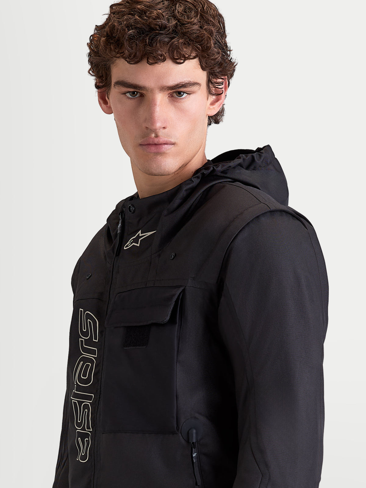 Alpinestars Morfex Parka Waterproof Jacket, men's urban motorcycle textile jacket in black, close-up portrait of a model wearing the jacket with an integrated hood and chest pocket details