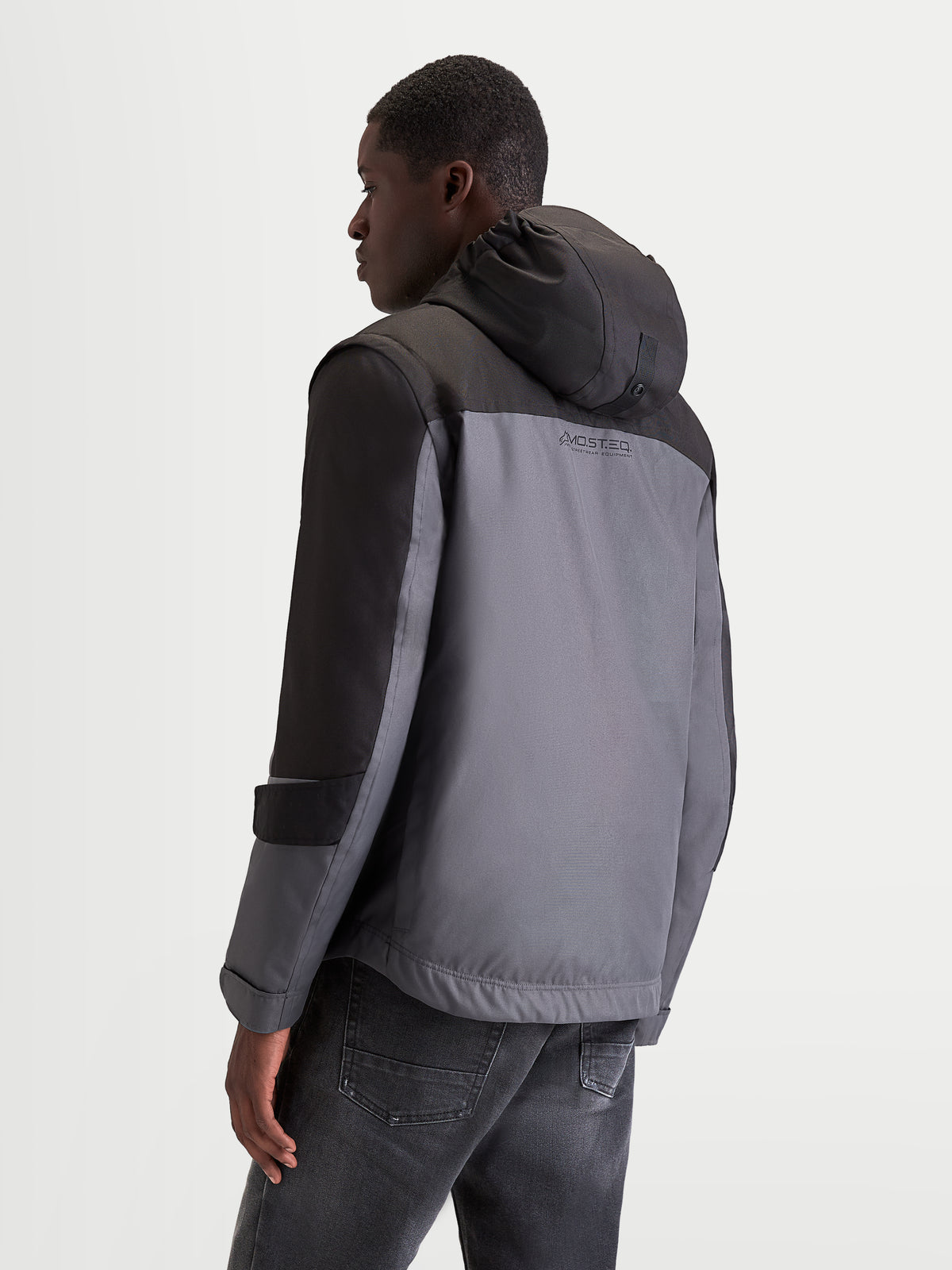 Alpinestars Morfex Parka Waterproof Jacket, men's urban contemporary motorcycle jacket in lunar gray and black, rear three-quarter profile view showing integrated hood and waterproof textile construction worn by a model.