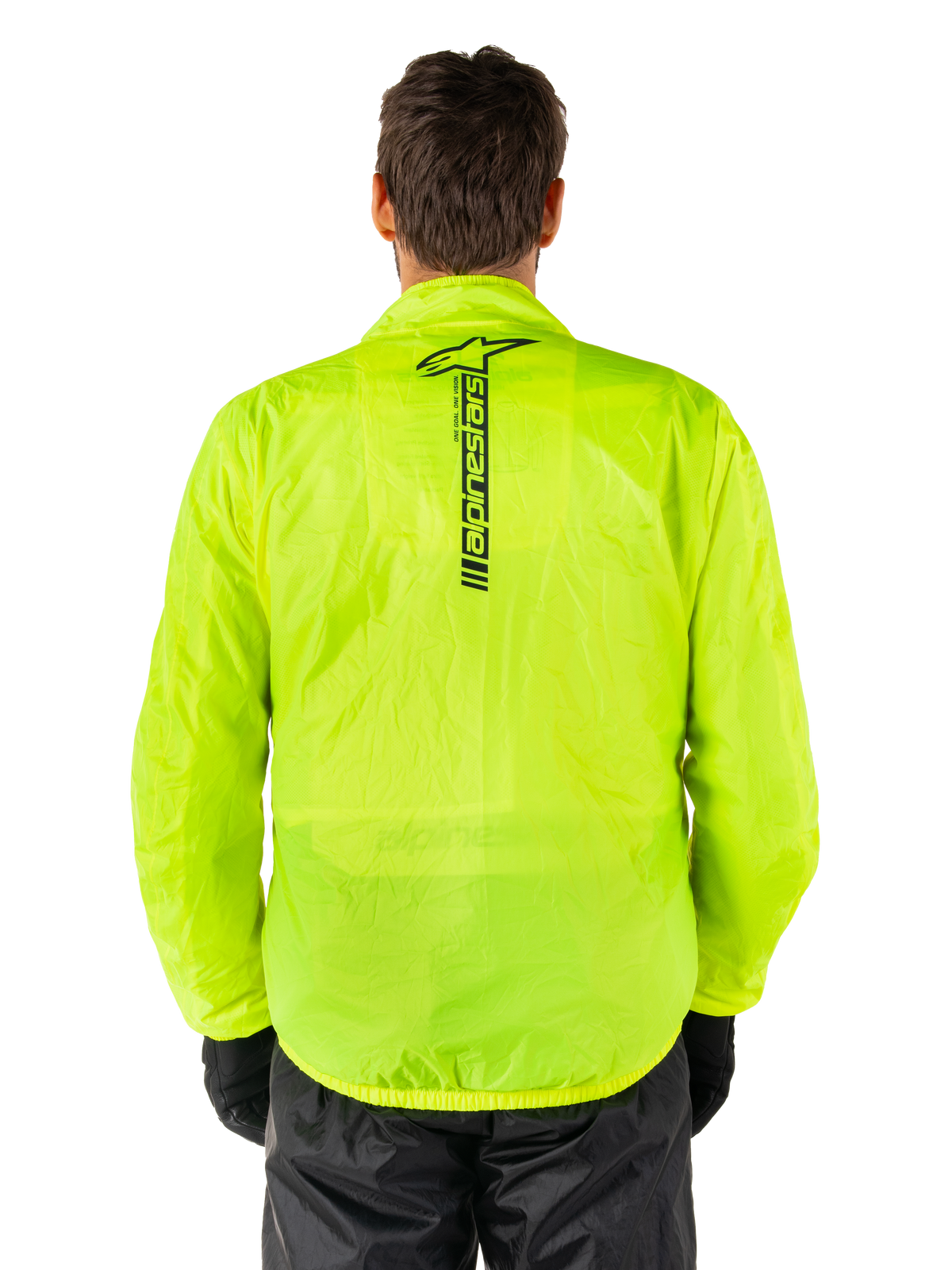 Alpinestars Hurricane Rain V2-jacka, regnjacka för motorcykel, Yellow Fluo, vy bakifrån som visar en vertikal svart Alpinestars-logotyp mitt på ryggen, lätt vattentätt material, bärs med svarta körbyxor och handskar