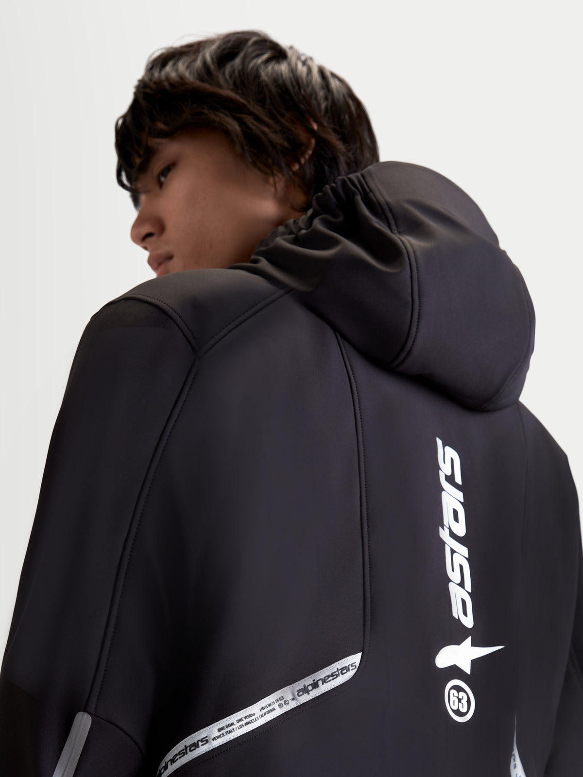 Alpinestars C 5 Drystar jacka, svart urban samtida motorcykeljacka för herr, vy bakifrån som visar integrerad huva och reflekterande designdetaljer, bars av en modell