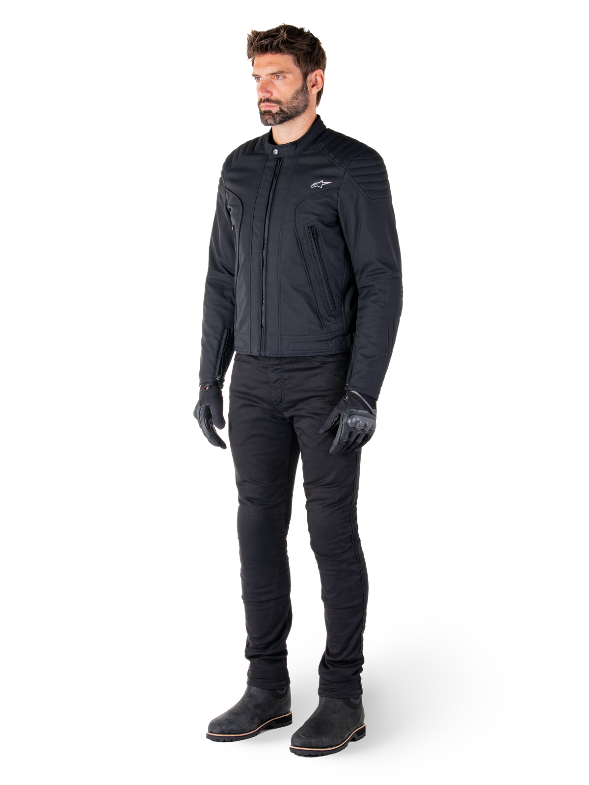 Male rider wearing the Alpinestars Clayton WR Jacket, Black urban motorcycle jacket, slim-fit design with quilted shoulder accents and matte finish, paired with black technical riding pants and gloves.