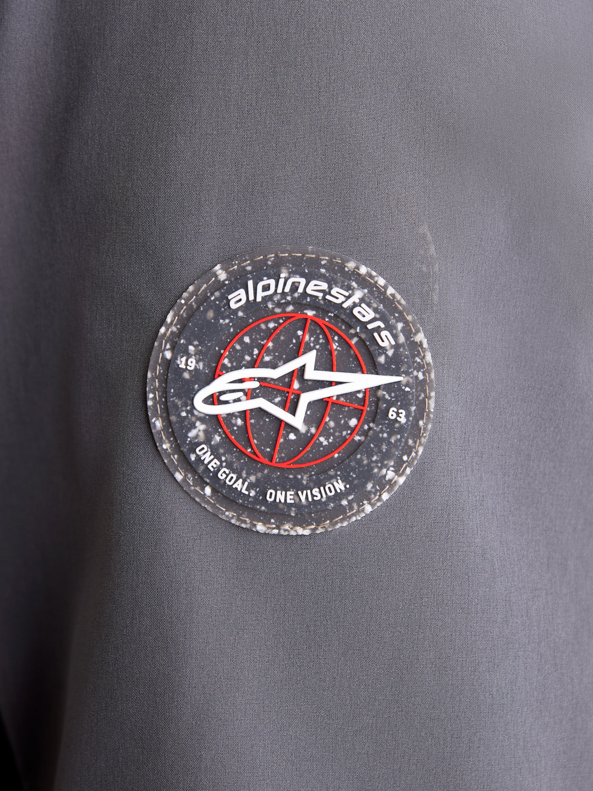 Alpinestars Therma Tech Wp Jk motorcykeljacka, närbild på det cirkulära logomärket på mörkgrå och svart ärm, som visar A-star-emblemet och signaturmärkning